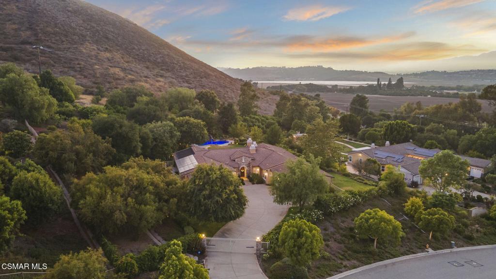 Expansive Private Retreat with Sunset Views in Thousand Oaks. Discover this rare single-story view estate nestled on nearly two acres of lush, landscaped grounds in a peaceful, gated enclave of Thousand Oaks. Boasting four spacious bedrooms, four bathrooms, and two oversized bonus rooms -- including a massive 20x20 space with its own private entrance -- this property is ideal for multigenerational living, a home-based business, or a luxury creative studio. Step inside to soaring vaulted ceilings, Brazilian cherry hardwood floors, and an open floorplan designed to maximize natural light and flow. From the moment you enter, a stunning sightline leads straight from the front door to the resort-style backyard and shimmering pool beyond. The gourmet island kitchen is a chef's dream, equipped with Miele, Wolf, and Sub-Zero appliances, custom wood cabinetry, and a layout perfect for entertaining. The family room, primary suite, and library/office each feature their own fireplaces, adding warmth and sophistication throughout the home. The luxurious primary suite offers a true retreat, complete with dual walk-in closets, private fireplace, and direct access to the backyard spa -- the ideal setting for peaceful mornings or evening relaxation. Step outside to your own private resort. The backyard features a gorgeous pool with waterfall, newer equipment including filter pump, heater, and capacitor, a dramatic fire features, a stand-alone spa, built-in BBQ, and newly installed flagstone hardscape. A flat, grassy yard offers space to play, entertain, or unwind, while an established orchard produces abundant citrus, guava, apricots, avocado, pomegranate, apples, and more. A lovely arbor-covered seating area adds a charming touch, perfect for enjoying golden hour views. Two large custom sheds provide ample storage in the side yard, while the home's owned solar system powers the pool and spa for maximum energy efficiency. Inside and out, the home is wired for sound with built-in speaker systems, and custom wood shutters add a timeless finish to the interiors. Backing to open space and the historic McCrea Ranch, this home offers unparalleled privacy and serenity, while still being conveniently close to local favorites like Underwood Farm, and just minutes from Westlake Village, Moorpark, Camarillo, and Simi Valley. Mature trees, large parcels, and quiet surroundings make this an exceptional opportunity to enjoy the best of California living -- all in one truly remarkable property.