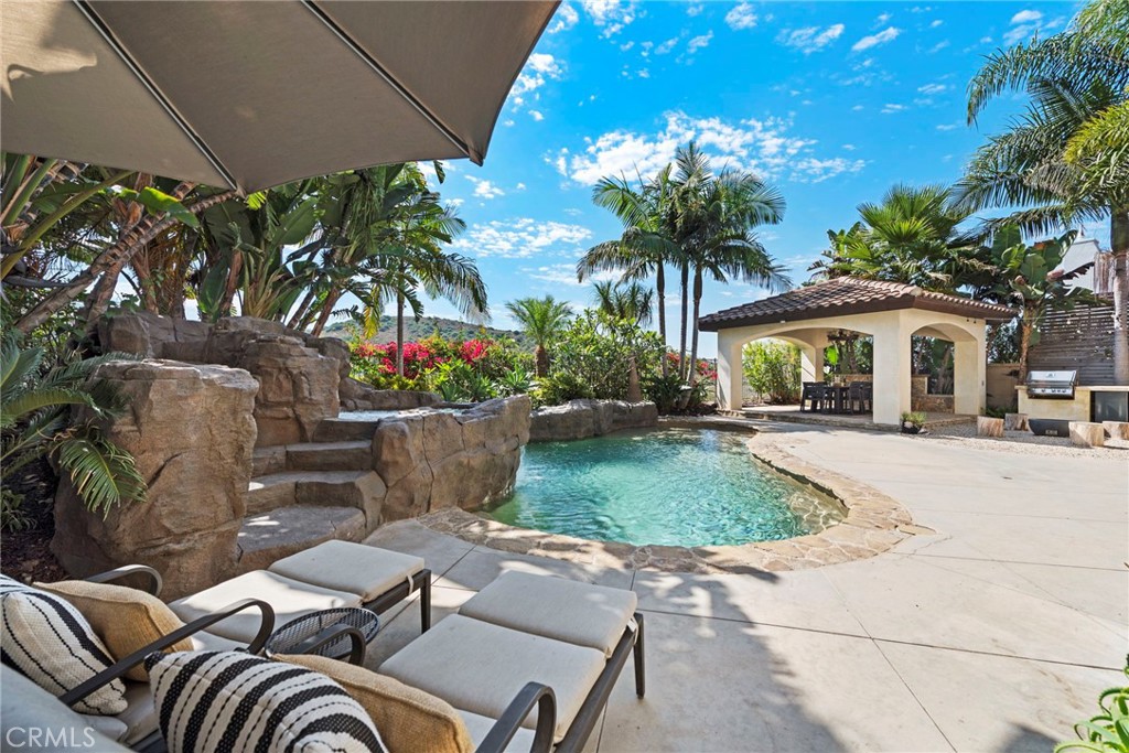 Welcome to this exquisite 5-bedroom, 5.5-bathroom semi-custom home located in the prestigious gated community of Careyes in Talega, San Clemente. Spanning approximately 4,689 sq ft, this luxurious property offers an idyllic blend of privacy, elegance, and coastal living on a serene single-loaded street. As you step through the entrance, you are greeted by an exposed-beamed loggia that opens into a peaceful courtyard, complete with a bubbling fountain and a cozy fire feature. Surrounded by lush landscaping, this space provides the perfect backdrop for intimate gatherings with family and friends. The detached casita, with its own private entrance, custom built-ins, and French doors opening to the courtyard, is ideal for hosting guests or serving as a studio, gym, or home office. The main home features sophisticated Santa Barbara-style finishes, with an abundance of natural light and exposed beams creating a warm, inviting atmosphere. High-end touches include travertine floors, granite countertops, and top-of-the-line stainless steel appliances. The open-concept floor plan is designed to seamlessly blend indoor and outdoor living, making it perfect for entertaining or enjoying quiet moments of relaxation. Two cast sandstone fireplaces, arched doorways, and expansive windows with French doors enhance the home’s ambiance of tranquility. The gourmet kitchen is a chef's dream, featuring Thermador appliances, a brand-new refrigerator, a large island, a butler’s pantry, and a cozy built-in desk area. The second floor offers a spacious bonus room with built-ins, a hidden mini-fridge, and a small library nook. The luxurious master suite includes a private balcony, a gas fireplace, and a spa-like bathroom with a walk-in shower, chromotherapy tub, seated vanity, and an expansive custom closet. The resort-style backyard is a true oasis, boasting a stunning rock pool and spa with a built-in water slide, a grand pavilion with exposed beams, a custom firewall with an integrated fountain, a fire pit, and a new built-in BBQ with a mini-fridge. This 10,237 sq ft lot offers sweeping golf course views that stretch all the way to the Pacific Ocean. Located near parks, trails, shopping, and dining, this home offers the perfect combination of luxury, privacy, and convenience. Don’t miss your chance to own this remarkable property. Schedule a viewing today and experience luxury living in Talega!