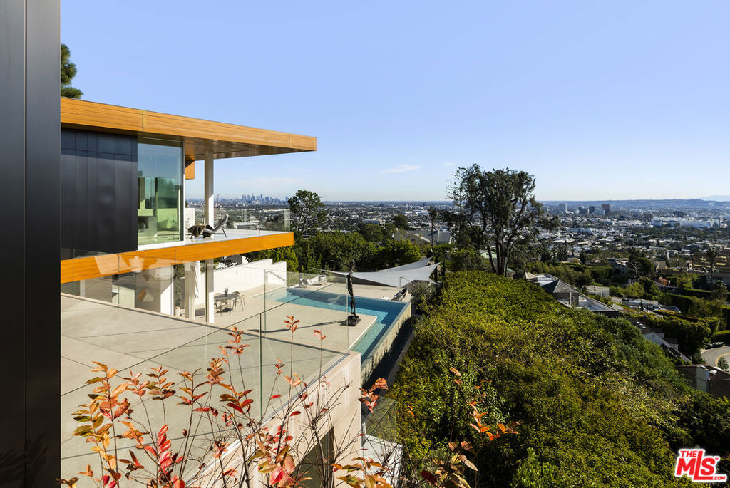 Acclaimed by Architectural Digest as a "sensational setting," this Sunset Plaza residence has paired the works of McRitchie Design & Gary Hutton Design, resulting in a steel-clad facade that gives way to a gallery-like simplicity infused with a warm ambiance. This distinctive home is crafted to showcase art of all proportions, the interior walls have plywood inserts to support hanging, while radiant heated floors, a top-tier home security system, elevator and smart home technology round-out the home's elevated features. Gleaming terrazzo floors, architectural lighting, and disappearing walls of glass showcase artwork, but also the astounding views from downtown to the ocean. An open floor plan encompasses the clean-lined kitchen and main living/dining areas, all with direct access to the expansive sundeck, taking in the unobstructed views and custom mosaic tiled pool. The primary suite sits wrapped in glass atop the residence, maximizing the outlook, while three secondary bedrooms, a plush media room, and another private outdoor deck complete the level. At the lower level, a guest unit with bath and kitchen opens to a substantial covered deck, offering an ideal space for gatherings of all sizes.