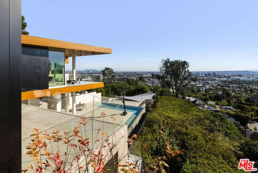 Acclaimed by Architectural Digest as a "sensational setting," this Sunset Plaza residence has paired the works of McRitchie Design & Gary Hutton Design, resulting in a steel-clad facade that gives way to a gallery-like simplicity infused with a warm ambiance. This distinctive home is crafted to showcase art of all proportions, the interior walls have plywood inserts to support hanging, while radiant heated floors, a top-tier home security system, elevator and smart home technology round-out the home's elevated features. Gleaming terrazzo floors, architectural lighting, and disappearing walls of glass showcase artwork, but also the astounding views from downtown to the ocean. An open floor plan encompasses the clean-lined kitchen and main living/dining areas, all with direct access to the expansive sundeck, taking in the unobstructed views and custom mosaic tiled pool. The primary suite sits wrapped in glass atop the residence, maximizing the outlook, while three secondary bedrooms, a plush media room, and another private outdoor deck complete the level. At the lower level, a guest unit with bath and kitchen opens to a substantial covered deck, offering an ideal space for gatherings of all sizes.