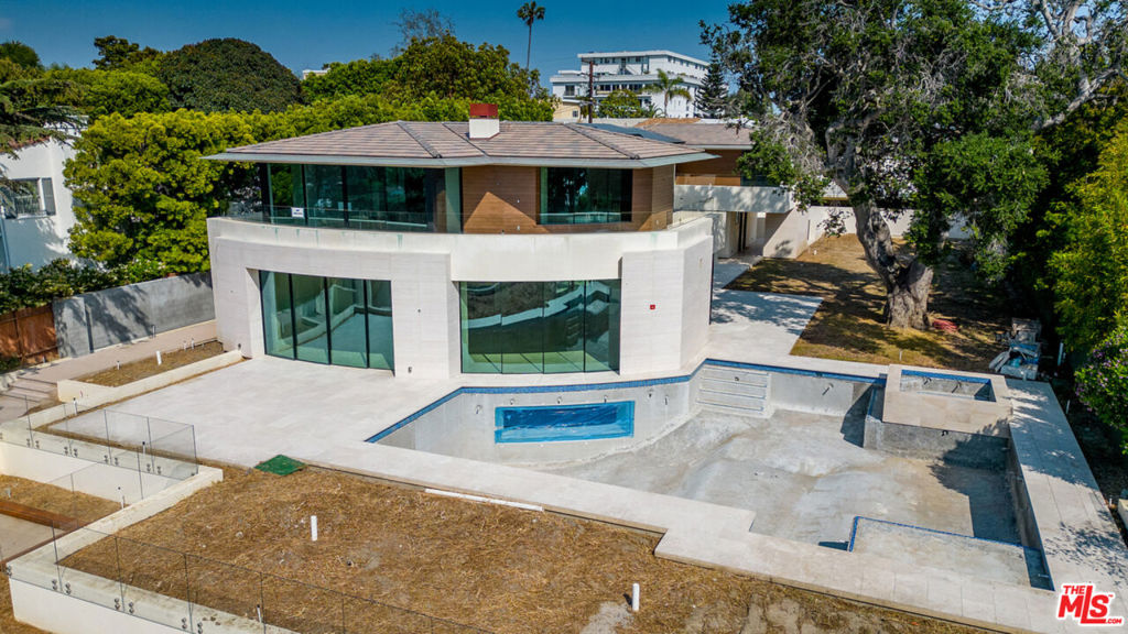 Every moment is elevated in this spectacular, nearly completed custom estate perched on one of Santa Monica's most desirable streets. Although construction is unfinished and ready for the new owner to resume, you can easily see how this home embraces indoor-outdoor living dappled in sunshine and wrapped in iconic views from the mountains to the ocean in this meticulously executed home. The sprawling layout begins with a sweeping great room and a massive gourmet kitchen. Walls of glass open the entire level to impressive al fresco entertaining spaces, including a pool, view deck, outdoor kitchen and dining patio. Upstairs, the palatial owner's suite boasts a private patio bathed in dazzling sunset vistas, while three luxurious secondary suites complete the level. A fifth suite is found on the ground level. The basement level is an ideal recreation destination featuring a wet bar, kitchenette and a window looking into the pool. Smart home controls, two laundry rooms, outstanding storage and a three-car garage await in this one-of-a-kind Santa Monica retreat, now ready for you to finish. Furnishings available for sale from the Seller.