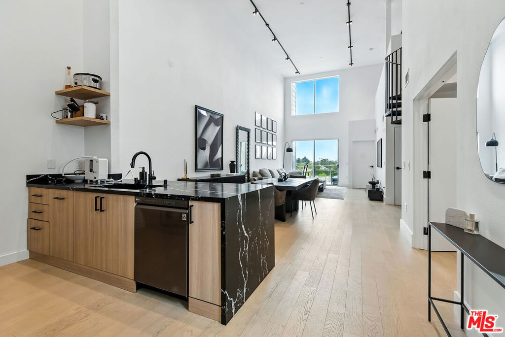 This stunning two-story penthouse offers 2 bedrooms, 2 bathrooms, plus a versatile loft (possible 3rd bedroom), with soaring nearly 20-foot ceilings. Walls of glass frame unobstructed city and mountain views stretching all the way to the Hollywood sign making this residence truly one of a kind. Designed with a sleek, contemporary aesthetic and recently renovated, the home is filled with natural light and features wide-plank white oak flooring throughout living spaces. The spacious living room flows seamlessly into the chef's kitchen, appointed with waterfall-edge Caesarstone countertops, a custom tile backsplash, stainless steel appliances, and a breakfast bar perfect for entertaining or everyday living. One patio extends from the open living and dining areas, creating effortless indoor-outdoor living. The primary suite is a tranquil retreat with a large walk-in closet and a spa-inspired en-suite clad in Carrera marble. A second bedroom also offers its own en-suite bath and custom closet, while the loft provides flexible space for a third bedroom, home office, or creative studio complete with its own 2nd private patio space. Additional highlights include in-unit laundry, central air and heat, custom lighting, two dedicated parking spaces with EV charging, and access to thoughtfully curated community amenities: BBQs, an outdoor fireplace, lounge seating, herb gardens, and citrus trees that create a serene urban oasis. Located in the heart of the Marina del Rey Arts District, this Silicon Beach adjacent residence is moments from Marina Marketplace dining and shopping, with easy access to the 90 freeway and LAX for a seamless coastal lifestyle.