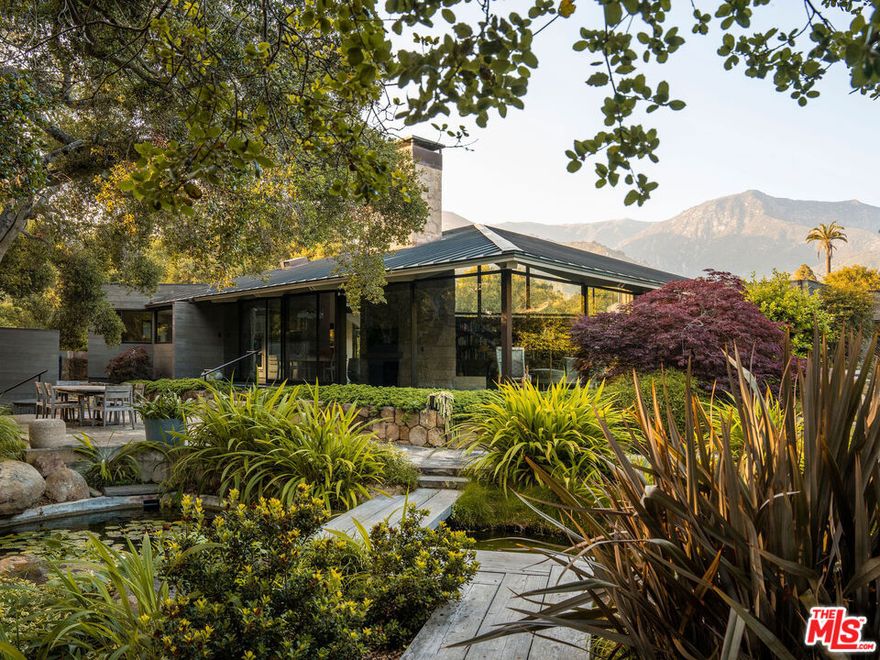 A rare midcentury modern architectural offering in the heart of Montecito, The Erving House, described as a "glass tent" by Time magazine in 1951,is a singular expression of architectural and landscape mastery, gracefully nestled on 2.7 acres of private, artfully curated grounds. Designed in 1950 by renowned architect Lutah Maria Riggs during her iconic modernist phase, and complemented by the legendary California landscape architect Thomas Church, this estate exemplifies the essence of indoor-outdoor living.Enter through private gates, where a meandering driveway weaves beneath a canopy of majestic oaks, setting a serene, cinematic approach to the residence. It culminates in a spacious motor court, where the home's striking flat-roof carport seamlessly marries form and function with timeless elegance.A covered walkway leads to the home's entrance, where a dramatic double-height foyer with floor-to-ceiling glass walls flood the space with natural light and frame expansive views of the surrounding landscape and mountains. This breathtaking entrance sets the tone for a home in constant dialogue with nature.The main living space unfolds with a soaring pitched ceiling, its apex seemingly reaching toward Montecito Peak, and a sculptural, biomorphic Santa Barbara stone fireplace, a subtle homage to Brazilian architect Oscar Niemeyer, Riggs' contemporary and collaborator. Walls of glass, both fixed and sliding, span the length of the room, opening to terraces and gardens and dissolving the boundaries between inside and out.The primary suite is a private retreat, featuring a spa-like bath, dual large dressing rooms, and tranquil views of the gardens and the coastal range. The home office offers inspiring solitude, framed by vistas of mature landscape and mountain ridgelines.The European-style kitchen is outfitted with custom Poggenpohl cabinetry and top-tier appliances, crafted with the serious chef in mind. The adjoining formal dining area also enjoys views of both the northern mountains and the home's terraced gardens and native flora beyond.Adjacent to the main house is a detached studio, providing flexible use, as a guest bedroom, creative workspace, or private retreat, its large windows revealing the natural beauty of mature oaks. Across the property is a serene 1-bedroom, 1-bath creekside guest house offering peaceful accommodations far enough from the main home to feel entirely its own.The grounds, once altered by previous owners,have been thoughtfully revived by landscape architect Susan Van Atta, who honored much of Church's original vision while adding her own artistry through native plantings. Wander through fruit orchards, lavender fields, and raised vegetable gardens, or enjoy a game at the bocce ball court, each element curated for both beauty, sustainability, and enjoyment.The Erving House is more than a residence, it is a living piece of architectural history and one of Montecito's most important homes. It offers unparalleled privacy, serenity, and a lifestyle that celebrates the seamless interplay between nature and design. Additional features include a high- functioning well with RO system for landscaping and a full power backup generator.