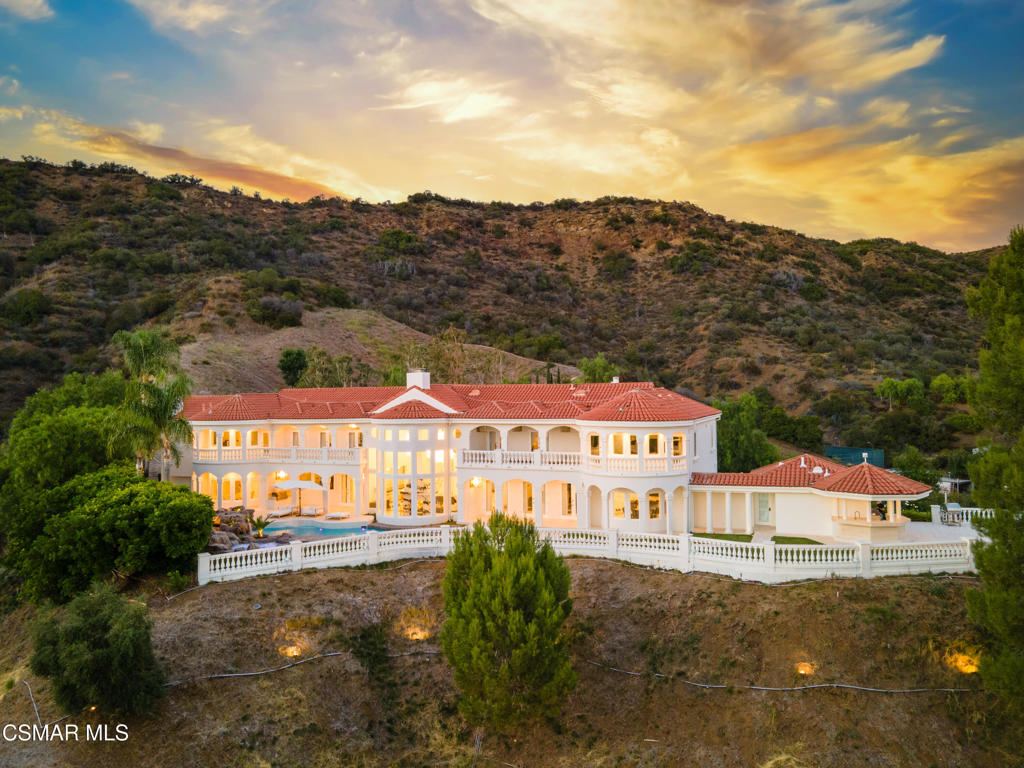 Tucked away on over 6 acres of privately gated land, this ultra exclusive Mediterranean Modern estate offers a perfect blend of seclusion, sophistication and convenience. Just minutes away from Malibu's world famous beaches, fine dining, and shopping, this 7-bedroom, 7-bathroom, 7547 sqft residence is a rare find for those who value both privacy and luxury. From the moment you step inside, the homes striking black, white and gold color palette sets it apart, creating an atmosphere of modern elegance that is simply unmatched. Soaring ceilings, floor to ceiling windows, and a grand crystal chandelier flood the living spaces with natural light, while bold black veined marble flooring and sleek gold accents add a touch of sophisticated opulence. The dramatic two-sided fireplace serves as a stunning focal point, seamlessly connecting the living and entertaining areas. Beyond the main residence, the estate also features a detached guest suite with private entrance and secluded patio, offering visitors or extended family members their own luxurious retreat. Step outside to experience a true resort-style oasis, where a sparkling pool reflects the breathtaking panoramic mountain views. Multiple terraces and manicured gardens provide the perfect setting for intimate relaxation or grand scale entertaining, ensuring that every moment here is one of absolute tranquility. With it's exclusive gated entrance, unparalleled modern design, and private guest accommodations, this Calabasas estate is a one-of-a-kind opportunity for the most discerning buyers.