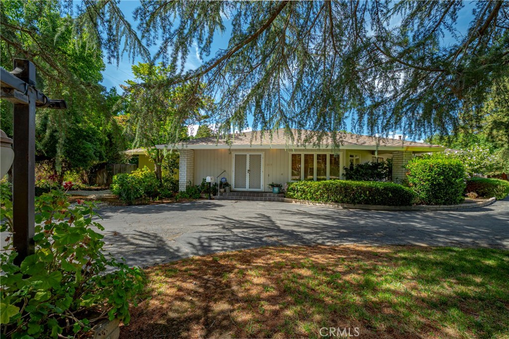 Located at the entrance of the desirable Mission Trails neighborhood, this charming 2-bedroom, 3-bathroom home offers 2,447 sq ft of spacious living on a generous 18,648 sq ft lot. Situated across from Bear Creek, the home boasts a serene, creek-side setting with mature landscaping and a welcoming circle driveway. Step inside to a grand living room featuring tall, beamed ceilings, built-in bookshelves, and a cozy brick fireplace. The sunroom provides a perfect spot for quiet reflection and views of the lovely backyard. The kitchen is outfitted with classic white cabinets, tile counters, and a convenient passthrough into the formal dining room—ideal for entertaining. The expansive primary suite impresses with an en-suite bathroom offering a separate tub and shower, a walk-in closet, and French doors that open to the sunroom. Enjoy indoor-outdoor living in the backyard oasis complete with a sparkling in-ground pool and custom built-in seating. The corner lot offers plenty of space for visitor and potential RV parking. Don't miss this opportunity to own this Bear Creek gem!