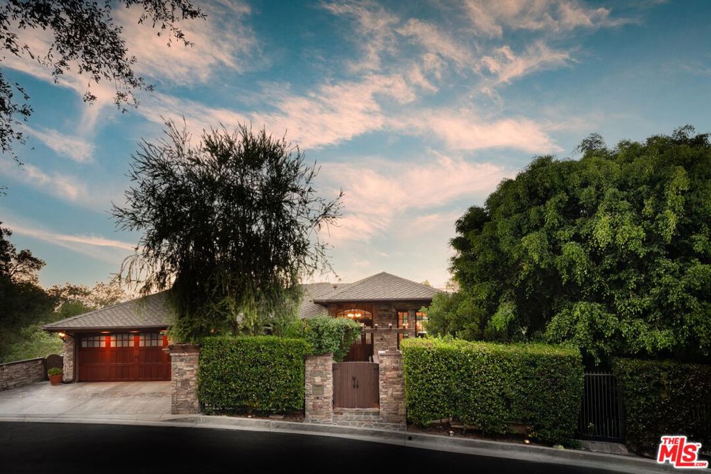 Set on a quiet cul-de-sac, this four bedroom, three and a half bath Studio City estate feels like a Lake Tahoe escape while offering LA convenience. Surrounded by sweeping unobstructed views and lush greenery, the home is designed for seamless indoor outdoor living with floor to ceiling glass doors opening to expansive wraparound decks. Inside, warmth and character abound with four fireplaces, a sprawling wine cellar, and a spa inspired primary suite featuring a rock pebble steam shower and soaking tub. The chef's kitchen is a true centerpiece, outfitted with Viking Professional appliances, handcrafted cabinetry, hammered copper sinks, dual pantries, two dishwashers, and a hand hewn granite island with a distinctive roped edge. The grounds feel like a private mountain retreat with a footbridge spanning a cascading waterfall and tranquil patios tucked into the landscape, while a lower level unfinished space offers flexibility for a future guest suite or ADU. Just minutes from major studios, Harvard Westlake, the Westside, and Ventura Boulevard's premier shopping and dining, this rare hideaway offers the perfect blend of Tahoe style serenity and Los Angeles lifestyle.