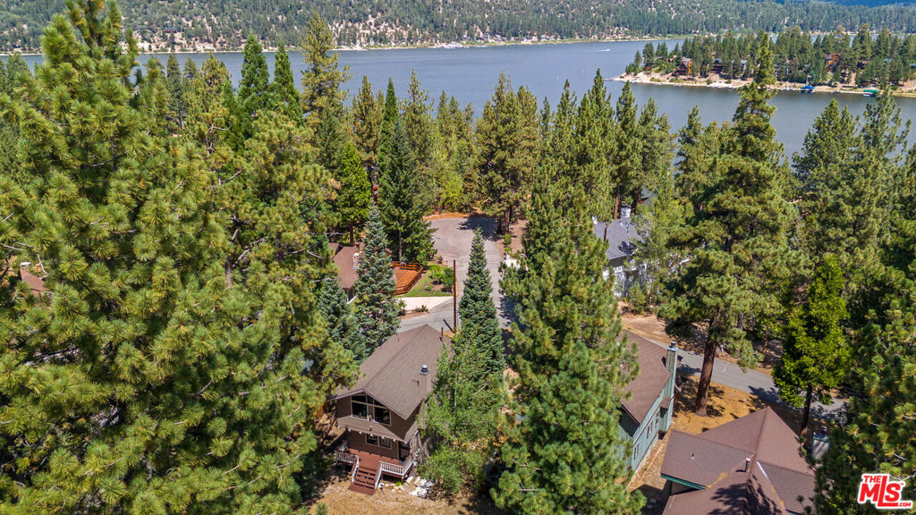 Just moments from the lake, this is the Big Bear cabin you've been waiting for, fully updated, stylishly furnished, and ready to enjoy. Tucked away on a quiet, secluded street with a rare street-to-street lot offering parking on both ends, this modern mountain retreat blends comfort, charm, and convenience. Step inside to a warm and inviting interior, beautifully remodeled with high ceilings, tongue-and-groove accents, and a stunning rock fireplace that anchors the spacious open-concept living area. Large custom wood windows flood the space with natural sunlight and frame tranquil views of sugar pines, blue skies, and even a peek-a-boo lake view from the upper deck. The layout is ideal, with two nicely sized bedrooms and a full bath downstairs, plus a bright and airy upper level featuring a half bath, upgraded kitchen, and plenty of room for family and friends to gather. Outdoors, three decks invite you to relax, entertain, and soak up the mountain air, whether under the sun or beneath starry skies. The property also offers ample space to park a large RV, boat, or trailer in the back, making it as practical as it is charming. Great for a high-end rental property, Airbnb-style investment, or simply your own private getaway, this cabin is equally perfect as a full-time retreat. Cozy, spacious, and move-in ready, your Big Bear escape awaits. Don't miss this rare opportunity. schedule your private showing today!