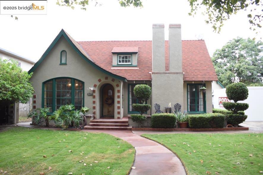Embrace the charm of this remarkable Tudor-style 3 bedroom, 2 bath home in the heart of Hughson. This home offers graceful arched doorways, warm hardwood floors, and sunlit living spaces, every detail tells a story of craftsmanship and care. The inviting living room features a classic fireplace framed by picture windows, while the formal dining room opens to a bright, cheerful kitchen. The spacious primary suite includes a private vanity nook and serene backyard views. Upstairs, flexible bonus rooms provide perfect spaces for an office, guest area, or creative retreat. Outside, entertain or unwind under the covered patio, complete with a built-in brick BBQ and lush garden setting. A detached two-car garage with workshop potential adds both function and charm. Set on a large 9,147 sq ft lot on a tree-lined street, this home beautifully blends vintage character with comfort — a rare opportunity to own a true Hughson treasure.
