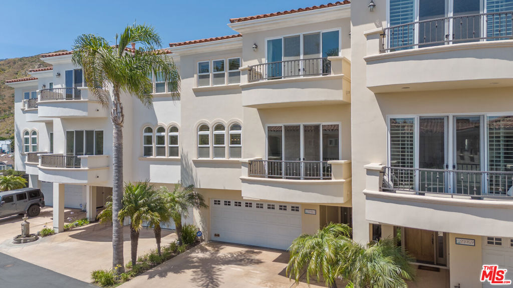 Welcome to coastal living in this beautifully upgraded 3-story townhome with ocean views, just minutes from Pepperdine and the beach. Ideal for those looking for space, privacy, and high-end amenities. The first floor offers a secure 2-car garage with overhead storage racks, built-in cabinetry, storage closets, and a whole-home Halo water filtration system. On the main level, enjoy an open-concept layout with soaring high ceilings and hardwood floors throughout. The formal living room features an elegant gas fireplace and balcony, while the dining room, breakfast bar, and chef's kitchen with Viking appliances, center island, pantry, and plenty of prep space make entertaining effortless. A bonus room currently set up as an office with a king size Murphy bed and closets can function as a third bedroom, guest room, or creative studio. It opens to a serene, fully fenced grassy yard - private, low-maintenance, and perfect for relaxing, gardening, or entertaining with a built-in gas line ready for a grill or firepit. A stylish guest bathroom and statement chandelier complete this floor. Upstairs, the primary suite offers sweeping ocean views from every window - including the bedroom, bathroom, shower, and soaking tub - plus a cozy gas fireplace, private balcony, and massive walk-in closet. The second bedroom has its own bath and balcony with mountain views. Luxurious travertine tile in the bathrooms adds a timeless, spa-like touch. A sunlit upstairs office with skylight and an in-unit laundry room with a sink and ample storage complete the top floor. Dual-zone A/C and heating systems allow for independent climate control on each floor, ensuring personalized comfort year-round. Smart Nest thermostats let you control the temperature remotely, and the home is pre-wired for ADT security for added peace of mind. Flexible layout, ocean views, multiple outdoor spaces, and top-tier finishes make this home a standout. Located in the exclusive 22-unit gated community of Toscana, residents enjoy access to a clubhouse, fitness center, heated pool and spa, beautifully landscaped grounds, security, and controlled entry. A pedestrian and bike path provides convenient access to Malibu Country Mart, Surf Canyon, Cross Creek Ranch, Bluffs Park, Malibu beaches, and Pepperdine. Don't miss your chance to live the Malibu lifestyle and unbeatable proximity to Malibu's best amenities.