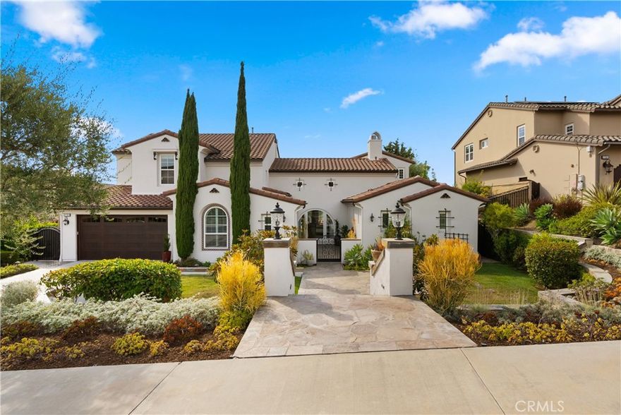 Blending timeless Spanish and Mediterranean influences, this residence is perched atop a ridge in the prestigious gated community of Rancho Madrina, showcasing panoramic views of the San Juan Capistrano hills, the historic Mission, and Marbella Golf Course. One of the community’s most sought-after floor plans, it features an oversized main-level primary suite thoughtfully positioned in its own private wing, with a versatile upstairs loft ideal for an office, gym, or lounge. A gated front courtyard framed by manicured landscaping sets the stage for refined craftsmanship throughout, where soaring beamed ceilings, a dramatic fireplace, glass doors, hardwood floors, crown molding, solid core doors, and custom built-ins define the great room and interior spaces. The gourmet kitchen boasts granite countertops, recently updated JennAir appliances, a beverage station, and spacious pantry, while the entertainer’s backyard offers a custom pool with waterfall features, spa, built-in BBQ, fire pit, and surround sound extending indoors and out. Additional highlights include a private office, dual-level laundry, upgraded HVAC, a 3-car tandem garage with epoxy flooring and garage doors replacement, epoxy-coated pipes, and freshly painted exterior—Ideally located near historic Downtown San Juan Capistrano, with easy access to Orange County’s beaches, parks, shopping, and major highways.