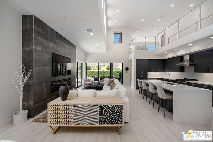 One of incredibly few FEE LAND homes that is walking distance to downtown Palm Springs and has uninterrupted panoramic southwestern mountain views - Enclave at Baristo is a prize. This sophisticated modern retreat is designed for effortless entertaining and seamless indoor-outdoor living. Every space has been thoughtfully curated with custom upgrades, refined finishes, and a focus on the breathtaking western mountain views that define Palm Springs living. The open-concept great room features soaring ceilings, walls of glass, and a dramatic fireplace anchored by large-format tile. A sleek chef's kitchen with waterfall-edge quartz island, Dacor suite of appliances, wine refrigerator, and ample storage flows beautifully into the dining and lounge areas. Upstairs, the primary suite offers a true sanctuary with a spacious walk-in closet, spa-style bath with dual vanities, and a glass-enclosed shower wrapped in designer tile. The loft provides flexible living perfect for a home office, den, or fitness area and opens to a covered patio with mesmerizing sunset views. The second ensuite bedroom sits privately on the main level for optimal separation and offers a huge en suite bath and walk-in closet. Outdoors, a sparkling pool and spa are framed by desert landscaping and striking mountain vistas, while multiple covered patios invite year-round dining and relaxation. With owned solar power and electric shades this home blends modern luxury with smart efficiency...all moments from downtown Palm Springs dining, shopping, and nightlife.