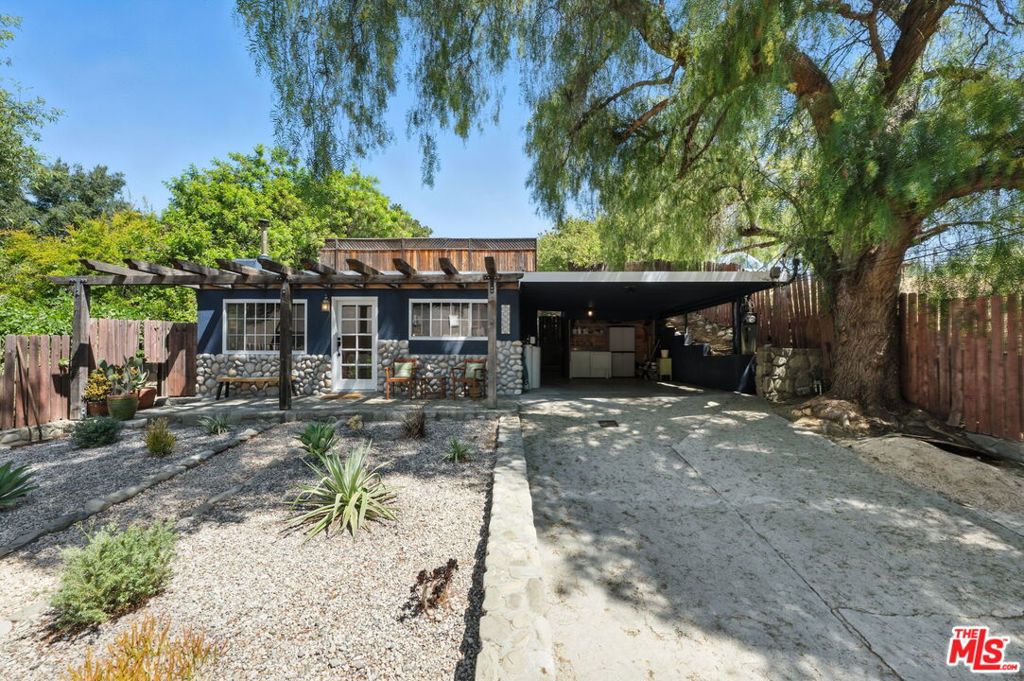 A rare opportunity to own a recently renovated, cozy canyon retreat with modern upgrades and income potential. Tucked away at the end of a quiet street, this updated Topanga gem offers privacy, character, and direct backyard access to scenic hiking trails. The moment you enter the gated driveway, a sense of calm that only Topanga delivers washes over you. Even more rare? Ample street parking, nearly unheard of in the canyon, with a covered carport, long driveway, and street parking. The open-concept layout flows around a striking Topanga River Rock fireplace, with new, real, herringbone white oak floors. Custom cabinetry anchors the interiors in warmth and craftsmanship. The kitchen and living areas connect seamlessly, creating the perfect backdrop for both everyday living and easy entertaining.Two light-filled bedrooms open to the outdoors through French doors, while the renovated bathroom features high-end tile work, premium hardware, and spa-like details. Upstairs, a rooftop deck offers a front-row seat to canyon sunsets and stargazing. The detached studio provides flexible living ideal for a home office, creative studio, guest suite, wellness space, or a private extra bedroom. Newly designed landscaping creates enchanting outdoor spaces with drought-tolerant plantings for easy, eco-friendly maintenance. With a brand-new roof, a new electric gate, and thoughtful updates throughout, the home is truly turnkey. And for those seeking passive income, it's already a high-performing Airbnb, fully operational with a trusted, built-in neighbor-manager. Perfectly located between the 101 and PCH, you're just 20 minutes to the coast, but a world away from it all. This is Topanga at its best, wild, refined, and ready for its next chapter.
