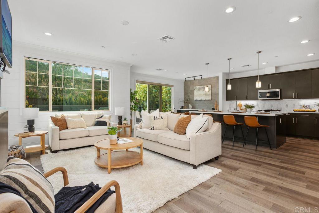 Nestled in The Preserve Community of Carlsbad—just a short distance from Carlsbad State Beach, shopping, and dining—this home offers the ideal combination of modern luxury and natural serenity. The expansive open-concept floor plan blends elegance, warmth, and functionality, featuring floor-to-ceiling cabinetry, wide-plank wood-like flooring, a cozy fireplace, a custom-built-in dry bar with beverage refrigerator, and elegant shiplap wall treatments throughout. The built-in ground jacuzzi with fire bowls and a custom water wall feature creates a private outdoor oasis ideal for both relaxation and entertaining. This home is loaded with upgrades, including a solar power system, whole-house fan, full-home water filtration, and Hunter Douglas custom window treatments. The chef-inspired kitchen serves as the heart of the home, boasting rich cabinetry, top-tier stainless steel appliances, a sprawling center island with quartz countertops, an oversized sink with pull-down faucet, stylish pendant lighting, and a sleek stone backsplash. Oversized sliding glass doors frame beautiful mountain views and open to your serene backyard retreat. Upstairs, you’ll find three bedrooms and a spacious loft with built-in cabinetry, offering a flexible space for any need. The primary suite showcases designer recessed wood wall paneling and a spa-inspired en-suite bathroom with dual vanities, a soaking tub, a separate walk-in shower, LED custom controlled mirrors, and a custom walk-in closet. The Preserve Community offers resort-style amenities, including a beach-entry pool with lap lanes, a jacuzzi, BBQ area with ample seating, outdoor lounge with fireplace, fitness center, gated dog park, playgrounds, parks, and hiking trails, all surrounded by approximately 156 acres of open space along scenic Quarry Creek, with top-rated schools nearby. Stop in grand opening Saturday 23rd Sunday 24th 1:00-4:00