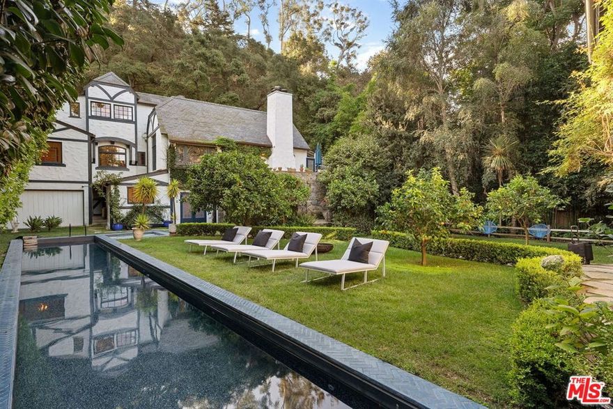 A moment in time...A magical chrysalis over almost 100 years has transformed an original 1928 weekend cabin, designed by Heth Wharton as a weekend retreat in the exclusive Rustic Canyon Uplifters Ranch, into the storybook reprieve that currently presents. A soulful 3-story English Tudor captivates with a sense of whimsy and irresistible character. Beamed cathedral ceilings and custom herringbone wood flooring coalesce classic and cool. Delightful stained-glass windows cast dancing colors throughout the day's evolving sunlight. Period vintage lighting elevates the emotional experience in each room. Each of the 5 en suite bedrooms offers a unique intimacy. The crowning third floor is a dreamy, sun-dappled, romantic primary retreat with tree-top views of the property's soothing grounds. The ground floor is believed to have been the genesis of the original 20's home which is emphasized by a theatrical lounge and an authentic speakeasy, still hidden behind secret doors, used to entertain members of the Uplifters during prohibition. Detached 3 car garage with spacious studio above. The most recent addition to this sentimental property is a sparkling saline +/- 54 foot saline swimming pool and jacuzzi. Expansive verdant environs marry a heavenly and enchanting estate in a divine canyon sanctuary.