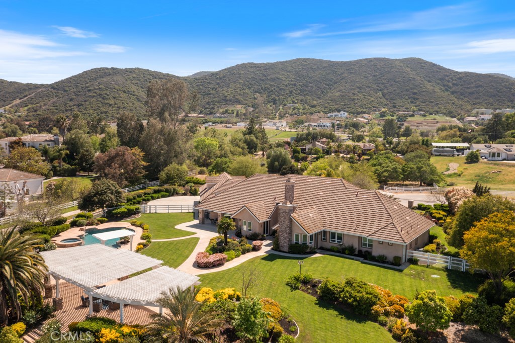 ***RARE CUSTOM LUXURY ESTATE WITH RESORT-STYLE SALTWATER POOL AND SPA ON 2.44 ACRES NESTLED IN THE LUSH GREEN HILLS OF WEST MURRIETA!!***WELCOME TO YOUR FOREVER HOME...A SPRAWLING CUSTOM MASTERPIECE PACKED WITH HIGH-END FEATURES AND PREMIUM MATERIALS OFFERING UNMATCHED LIFESTYLE***Featuring 5 Oversized Bedrooms, a Dedicated Home Office, 5 Bathrooms, a MASSIVE BONUS ROOM (approx 1200 sf in addition to the 5400 sf listed on the MLS), and a 4-Car Drive-Thru Garage! This Estate Checks Every Box! FULLY-PAID 50-PANEL SOLAR, EXPANSIVE PROFESSIONAL LANDSCAPE, PRIVATE WELL AND ENDLESS VEHICLE PARKING! From the Moment You Enter the Majestic Double Doors, You Are Greeted by Towering Coffered Ceilings, Crown Molding, Chandeliers and Lighted Art Niches. Off the Grand Foyer, the Formal Living and Dining Rooms Exude Elegance with Double Crown Molding, Custom Drapery, View Windows and a Deco Fireplace. Designed to Impress and Built to Entertain, the Chef’s Dream Kitchen is a Showstopper! Endowed with Premium Cabinetry, a Massive Island/Breakfast Bar, New Quartz Counters and High-End Jenn Air/Kitchen Aid Appliances...You Are Set to Host Your Prized Events! Cook to Your Hearts Delight with Built-In Double Ovens, a 6-Burner Stove w/Griddle, 2 Dishwashers and an Oversized Refrigerator-Freezer! The Adjacent Family Room Offers Panoramic Backyard Views, a Large Flagstone Fireplace, Sizeable Ceiling Fans, and Built-In Speakers. French Doors lead to Your Private Outdoor Paradise—and Wait Until You See It…THE ENTERTAINER'S BACKYARD IS STRAIGHT OUT OF A 5-STAR RESORT! The Massive 65’ Pergola with Flagstone Columns, Sparkling Pebble-Tec Saltwater Pool with Baja Shelf, Deep End, Waterfalls/Jets, 12-Seat Spa and Stamped Concrete Decking will be the Delight of Unforgettable Celebrations All Year Long! The Primary Suite/Retreat is a Spacious 32' Sanctuary with a Cozy Fireplace, Custom Dual Closets with Extravagant Built-ins, and Backyard Access. The Newly Remodeled Luxury Primary Bathroom/Spa features a Freestanding Soaking Tub, Dual-Sink Quartz Vanity, Private Toilet Room, and an Epic Walk-in Shower with 4 Heads, a 3-Person Bench, and a Classic Pebble Tile Floor. Each Secondary Bedroom is a Retreat in Itself—Offering Stunning Views, Closets with Built-ins and Attached or Adjacent Bathrooms. The Laundry Room is To Die for, and the HUGE BONUS ROOM Over the Garage is IDEAL as a Game Room, Gym or SEPARATE ADU! This is a Once-in-a-Generation Opportunity! SEE SUPPLEMENT FOR FULL FEATURE LIST!