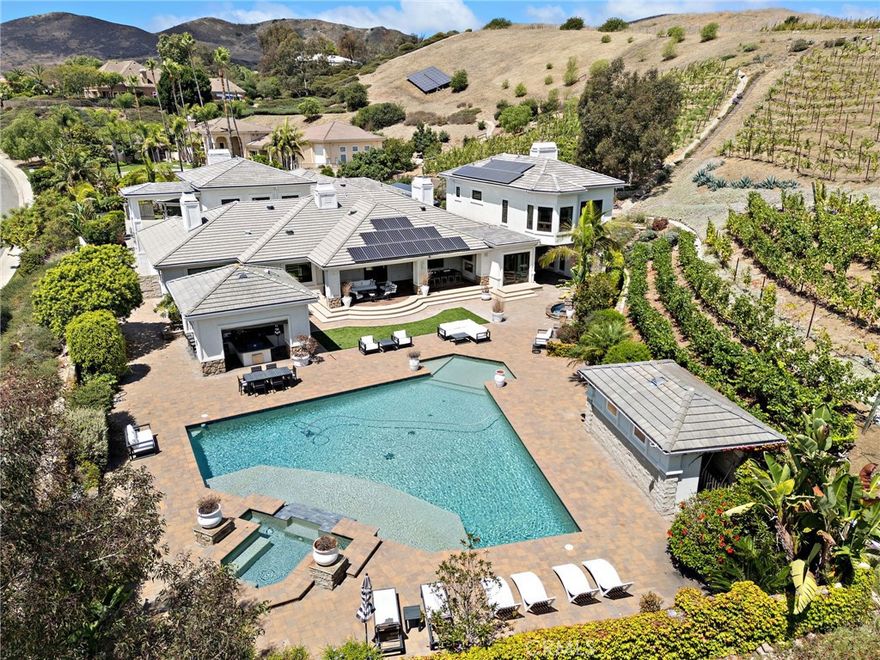 Sophisticated Coastal Estate on 2.65 Acres | 8-Car Garage | Vineyard | Movie Theater ...  Offered FULLY FURNISHED!!



HUGE price reduction!  Just bring your suitcase and move into this incredible masterpiece.  Nestled on an expansive and premier over-sized lot, this extraordinary custom estate offers unmatched privacy, luxury, and lifestyle across 2.65 acres of refined coastal living. Beyond the double iron gates, a grand circular motor court with a central fountain welcomes you—complete with ample guest parking and space for a recreational vehicle.  Car enthusiasts will appreciate the 8-car (2,000 sqft) garage with vaulted ceilings, tons of built-in storage, and its own bathroom!



Covered entryway with glass panel doors leads you into 7,200 sqft of downstairs living space which includes a light-filled, two-story decadently-furnished living room, powder room, wine room, home theater fit for a movie mogul, gourmet kitchen with quartz countertops and hidden tv that descends from the ceiling, family room, main-floor master suite (on the East wing).



The estate features dual master suites, both upstairs and downstairs, situated at opposite ends of the home for ultimate privacy. The upstairs primary suite spans over 1,500 sq ft and includes a secret 350 sq ft custom closet—a true showstopper for anyone who needs an ultimate closet like no other.  The huge main-level master and extra-large walk-in closet provides ideal single-level living or guest accommodations.  Three additional large bedrooms offer space and comfort for everyone.



The 8-person state-of-the-art theater offers loungers for each viewer, along with a snack bar, and its own bathroom.  Outdoors, enjoy a resort-style backyard with a diamond-shaped pool and spa, a covered outdoor kitchen and bar, outdoor shower, and built-in surround sound for seamless indoor/outdoor entertaining.



Nestled among flourishing citrus and stone fruit orchards, this exceptional property also features thriving avocado trees, creating a lush and bountiful landscape.  A true highlight is the private vineyard, which will yield an impressive 2,000 bottles of wine this year—bringing the charm, flavor, and romance of wine country right to your own backyard.



This is more than a home—it’s a lifestyle.  This property must be seen to be fully appreciated.
