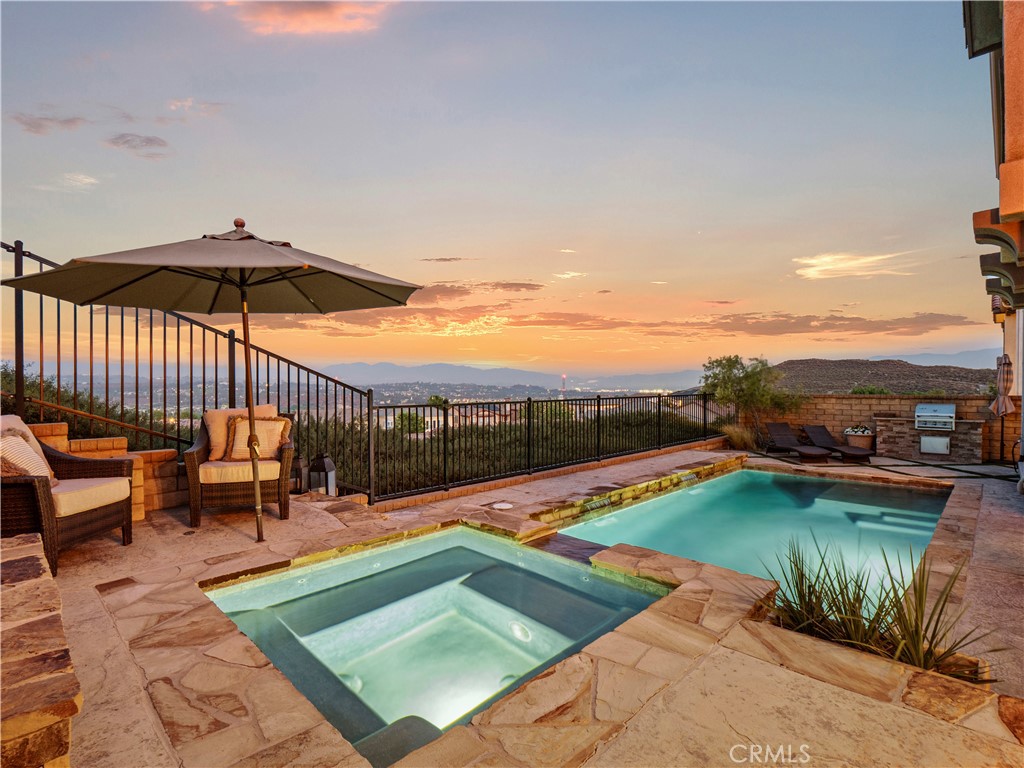 Breathtaking 4 BD, 3 BA Pool Home w/ Panoramic Views in the Gated West Hills Community with a Bed & Bath Downstairs, Solar & a Large Loft! Welcome to this home offering over 2,700 sq ft of luxurious living, & unobstructed views from all main living areas & the primary suite, this home blends comfort, elegance, & functionality. Enter through the formal entry w/ stone accent walls & soaring ceilings into an open floor plan filled w/ natural light & stylish upgrades. Plantation shutters & upgraded light fixtures give the home a designer feel. The expansive great room features a cozy brick fireplace, custom shiplap wall, & incredible backyard & mountain views. The dining area & kitchen offer the same views & are perfect for entertaining. The chef’s kitchen boasts a massive center island w/ stone accents, granite counters, espresso cabinetry, stainless steel appliances including a double oven, & a walk-in pantry w/ extra-deep storage & built-in cabinetry. Additional understairs storage enhances functionality. A spacious downstairs bedroom & beautifully appointed full bath offering guest or multigenerational living options. Upstairs, the large loft serves as a secondary living area, media room, office, or playroom. The primary suite is a retreat w/ stunning views, & a luxurious ensuite bath featuring a soaking tub, glass-enclosed shower, dual sinks, vanity, & oversized walk-in closet. Two additional bedrooms are generously sized w/ walk-in closets, & one features a charming custom shiplap accent wall. The full upstairs bathroom includes dual sinks, & the spacious laundry room is complete w/ storage, a utility sink, & a large walk-in linen closet. Step outside to your private entertainer’s paradise, where a large covered patio w/ a ceiling fan overlooks a sparkling pool & spa w/ cascading waterfalls. The backyard is perfectly designed for relaxation & entertaining, w/ a built-in lounge areas, a firepit, & a custom-built BBQ station. One side yard includes a built-in basketball hoop, while the other offers a dedicated dog run w/ a built-in doggie door leading inside. The 2-car garage includes epoxy floors & storage. Enjoy all the amenities West Hills offers: three resort-style pools, clubhouse, playground, firepit, & miles of trails. Conveniently located near shopping centers, West Hills Park, & top-rated schools including West Creek Academy, Rio Norte Junior High, & Valencia High w/ easy access to the 5 freeway making this home perfect!!!