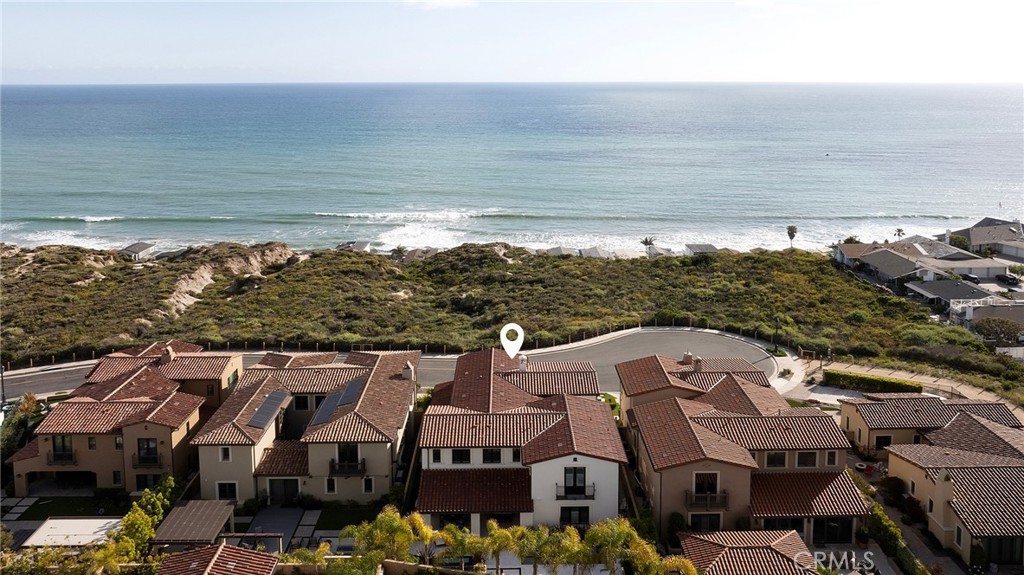 From the historic San Clemente Pier to Dana Point’s sculpted Headlands and the distant silhouettes of Catalina Island, sweeping panoramic views of the Pacific form the ever-changing backdrop to this custom-caliber residence—an elevated offering within the Azure Viewpoint Collection at Sea Summit in San Clemente. Ideally positioned on a single-loaded cul-de-sac framed by protected coastal bluffs, canyon trails, and the raw beauty of preserved open space, the Mediterranean-inspired home welcomes with a covered front patio and fireplace, extending into a sun-drenched ocean-view terrace wrapped in curated hardscaping and lush landscape design. Inside, an expanded floorplan of approximately 4,880 square feet unfolds with quiet grandeur—offering four ensuite bedrooms and four-and-one-half baths, including a refined main-level suite. Soaring ceilings, wide passages, and disappearing walls of glass create a seamless dialogue between indoors and out, with custom built-ins framing the great room’s fireplace and carrying into a dining room that connects effortlessly to both the backyard and an exquisitely appointed kitchen. The kitchen itself is magazine-worthy: a generous quartz island with seating for six, white Shaker cabinetry, artisan tilework, dual pantries—including a walk-in with integrated beverage station—and professional-grade appliances by Sub-Zero, Wolf, and Asko. A dramatic staircase, anchored by a custom desk niche, leads to a sunlit landing, versatile bonus room, and a serene primary suite where a covered balcony captures the horizon. The suite offers a retreat-like sitting area, boutique walk-in closet with direct laundry access, and a spa-like bath with freestanding tub, dual-entry shower, and uninterrupted views of whitewater and sky. Outside, a private loggia, cascading spa, open-air fireplace, and built-in BBQ kitchen complete the home’s outdoor experience—crafted for unforgettable entertaining. Built by acclaimed luxury builder Taylor Morrison, this residence enjoys access to the exclusive Summit Club, a 21,000-square-foot coastal haven with ocean-view pool, spa, fitness center, and entertaining lounge. The Sea Summit lifestyle also includes award-winning schools, access to trails and beaches, and proximity to the shops and dining of the Outlets at San Clemente.