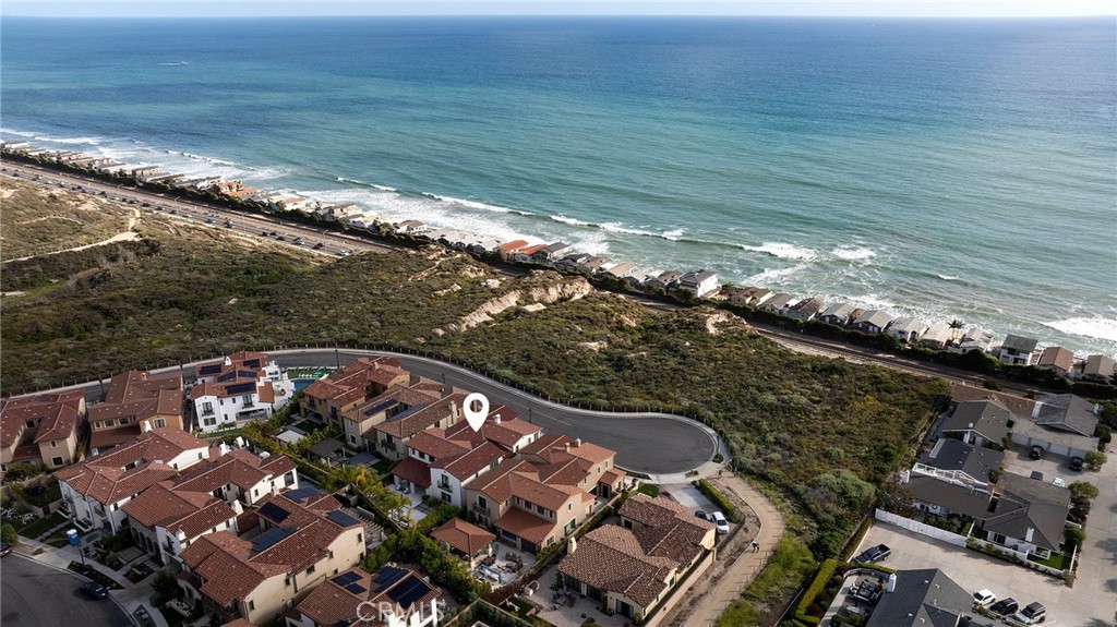 From the historic San Clemente Pier to Dana Point’s sculpted Headlands and the distant silhouettes of Catalina Island, sweeping panoramic views of the Pacific form the ever-changing backdrop to this custom-caliber residence—an elevated offering within the Azure Viewpoint Collection at Sea Summit in San Clemente. Ideally positioned on a single-loaded cul-de-sac framed by protected coastal bluffs, canyon trails, and the raw beauty of preserved open space, the Mediterranean-inspired home welcomes with a covered front patio and fireplace, extending into a sun-drenched ocean-view terrace wrapped in curated hardscaping and lush landscape design. Inside, an expanded floorplan of approximately 4,880 square feet unfolds with quiet grandeur—offering four ensuite bedrooms and four-and-one-half baths, including a refined main-level suite. Soaring ceilings, wide passages, and disappearing walls of glass create a seamless dialogue between indoors and out, with custom built-ins framing the great room’s fireplace and carrying into a dining room that connects effortlessly to both the backyard and an exquisitely appointed kitchen. The kitchen itself is magazine-worthy: a generous quartz island with seating for six, white Shaker cabinetry, artisan tilework, dual pantries—including a walk-in with integrated beverage station—and professional-grade appliances by Sub-Zero, Wolf, and Asko. A dramatic staircase, anchored by a custom desk niche, leads to a sunlit landing, versatile bonus room, and a serene primary suite where a covered balcony captures the horizon. The suite offers a retreat-like sitting area, boutique walk-in closet with direct laundry access, and a spa-like bath with freestanding tub, dual-entry shower, and uninterrupted views of whitewater and sky. Outside, a private loggia, cascading spa, open-air fireplace, and built-in BBQ kitchen complete the home’s outdoor experience—crafted for unforgettable entertaining. Built by acclaimed luxury builder Taylor Morrison, this residence enjoys access to the exclusive Summit Club, a 21,000-square-foot coastal haven with ocean-view pool, spa, fitness center, and entertaining lounge. The Sea Summit lifestyle also includes award-winning schools, access to trails and beaches, and proximity to the shops and dining of the Outlets at San Clemente.