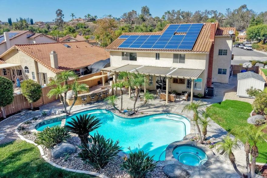 This Rancho Arbolitos Polo model is absolutely gorgeous! Situated on a quarter-acre lot with potential RV and boat parking, this home offers both beauty and functionality. As you enter, you’ll appreciate the cathedral ceilings, gleaming hardwood floors, large baseboards, crown molding, and elegant wrought iron staircase. The delightful kitchen features granite counters, soft-closing cabinetry, stainless steel appliances, a farmhouse sink, six-burner gas cooktop, pendant lighting, bar seating, and a walk-in pantry. The entertainer’s backyard feels like a private resort with a custom-designed pool and spa, a large pergola with ceiling fans, grassy areas, palm trees, and a true tropical vacation vibe. You’ll love the built-in bar with a pizza oven, barbecue, refrigerator, and additional bar seating — perfect for gatherings and outdoor dining. Additional highlights include a downstairs bedroom with a full bathroom and upgraded secondary bathrooms. The primary suite offers vaulted ceilings, a large walk-in closet, a new jetted tub, dual vanity sinks, and a standalone shower. This home also includes a huge bonus room with an additional guest quarters — ideal for use as a game room, guest suite, additional living area or home theater. Located in the award-winning Poway Unified School District with no HOA and no Mello-Roos fees!