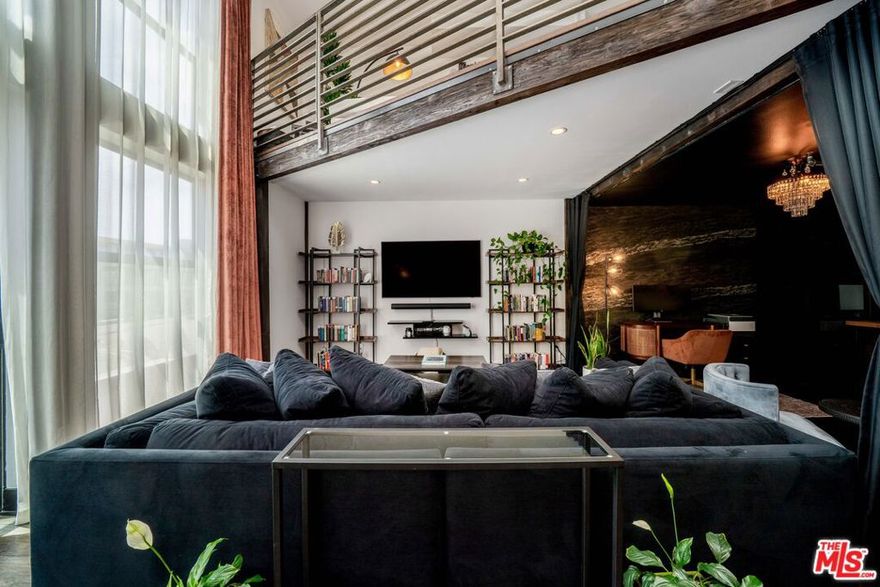 If you enjoy loft living, welcome to this stunning, remodeled top-floor loft, a true entertainer's dream tucked into the Marina's most dynamic and creative streets. Thoughtfully curated with high-end finishes and smart design, this condo blends dramatic architecture with modern comfort. Soaring 17+ foot ceilings and a wall of floor-to-ceiling windows flood the space with natural light, framed by a custom motorized drapery that adds a bold designer touch. The open-concept layout includes a custom speakeasy-style bar, perfect for unwinding after a long day or kicking off an evening of entertainment or relaxation. The kitchen is a showpiece, featuring quartz countertops and a suite of top-tier appliances including a Viking Pro refrigerator, Ilve range, and Fisher & Paykel dishwasher. Both bathrooms are elevated with copper sinks, marble counters, custom-tiled showers, smart mirror lighting, and Toto bidet toilets. A private guest bedroom with en-suite bath is located on the main level, while the upstairs mezzanine hosts a spacious primary suite with a walk-in closet, room for a home office, and serene architectural views. Additional highlights include new HVAC 2024, custom cabinetry and doors, upgraded lighting, EV charging, guest parking, and a rooftop deck with city views.