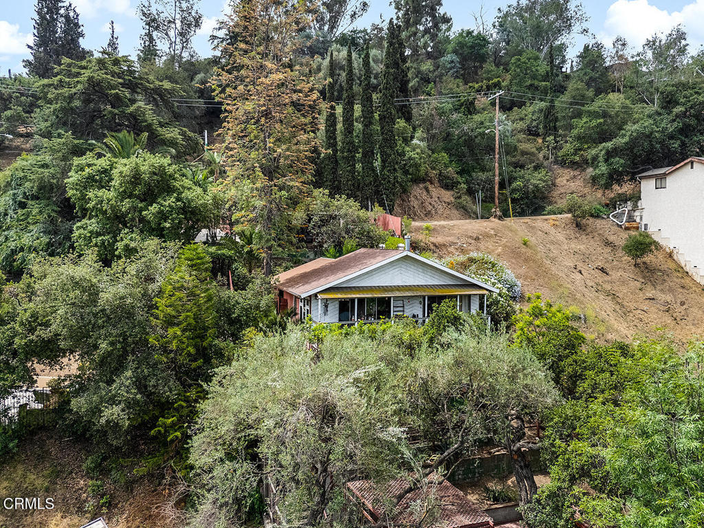 Tucked behind a fence on a peaceful hillside, Casa Escalon feels like a secret garden in the city. With treetop views stretching to the mountains and the iconic Eagle Rock, this 1,615 sq. ft. home on a generous 7,944 sq. ft. lot invites you to create your own private sanctuary.A series of terraces and decks wind through the lush, multi-level yard--each space offering a new perspective and purpose, whether it's morning coffee under the oaks or evenings spent watching the light shift across the hills. Inside, the living room opens to a wide deck that runs the width of the home, perfect for indoor-outdoor living. Spanish-style beams and a graceful archway add charm and character, leading into the dining room and kitchen.The main level also features a bedroom with ensuite full bath, while the lower level offers two rooms with closets that can serve as tandem bedrooms, a den and guest space, or a creative studio setup. A second full bathroom and laundry room with extra storage are located downstairs as well, along with a sliding door that opens to the backyard.There is gated off-street parking for at least two cars, with a carport and driveway space, along with additional storage space in a shed.From the oak tree-shaded deck to the sunlit terraces below, the outdoor space is layered with possibility. Garden, play, entertain, or just retreat - Casa Escalon offers the freedom to dream.