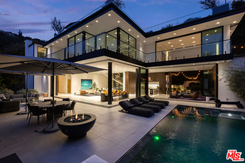 This ultra-private Organic Contemporary estate has been meticulously crafted to meet the highest standards of luxury. Encompassing approximately 7,000 square feet of voluminous living space, the home blends modern design with natural elements, offering exceptional scale and an abundance of natural light throughout. A dramatic entry begins at a custom double-height Brazilian Monkeywood pivot door, leading into a grand, light-filled foyer. Seamless indoor-outdoor living is achieved with disappearing walls of glass that open to an expansive pool area complete with an outdoor kitchen, BBQ, firepit and integrated smart home features throughout the property. Designed for both grand entertaining and intimate living, the residence includes four luxurious bedrooms all with en-suite bathrooms, a state-of-the-art home theater, a wine-tasting and billiards lounge, and a fully outfitted basement bar. The opulent primary suite offers a sanctuary of style and comfort. The one-of-a-kind rooftop deck, showcases panoramic views of the skyline - a perfect backdrop for sunset entertaining or quiet evenings under the stars. This is the perfect Hollywood Hills retreat. A true collector's home for the most discerning Buyer.