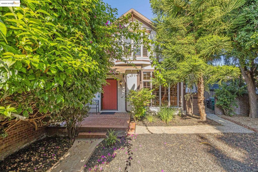 Tucked behind a private gate in Oakland’s vibrant Oak Tree neighborhood, this extraordinary Craftsman-style residence reveals a hidden world of light, space, and privacy. Once a carriage house, it has been thoughtfully updated while honoring its rich architectural character. The open floor plan features soaring ceilings, exposed beams, and a striking fireplace with custom iron screen doors anchoring the living and dining areas, perfect for gatherings. The sunny kitchen blends style and function with stone countertops, stainless appliances, and tile flooring. A half bath and laundry room on the main level enhance the home’s comfort and flow. Freshly refinished wood floors extend through the main living areas and bedrooms, adding warmth and continuity throughout. The spacious full bath offers a separate shower and deep soaking tub for relaxation and quiet luxury. Just outside, a lush garden sanctuary framed by mature trees and flowering shrubs effortlessly extends living outdoors. A charming detached studio, generous storage, and proximity to BART and Lake Merritt complete this rare retreat.