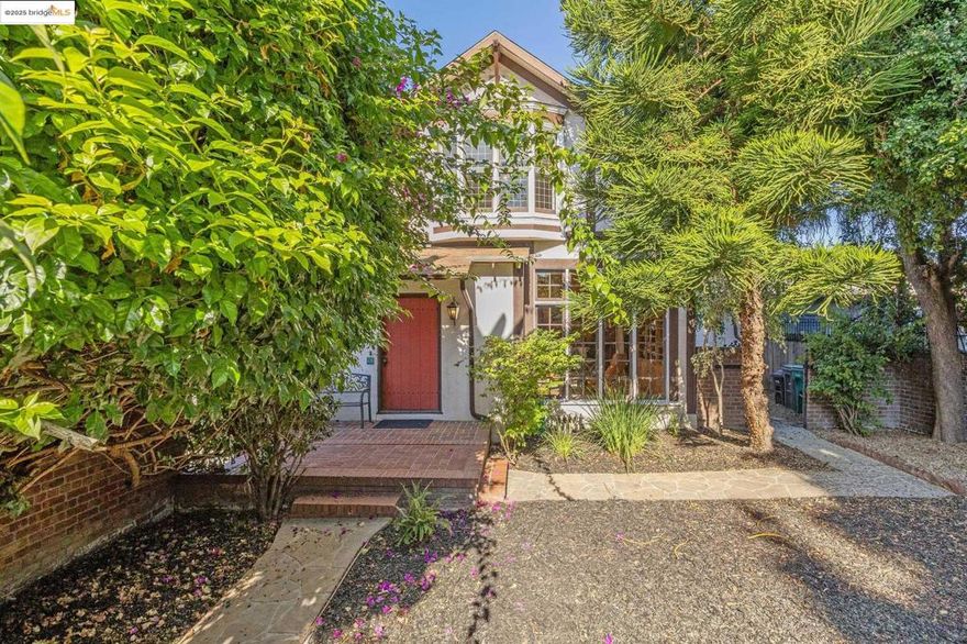 Tucked behind a private gate in Oakland’s vibrant Oak Tree neighborhood, this extraordinary Craftsman-style residence reveals a hidden world of light, space, and privacy. Once a carriage house, it has been thoughtfully updated while honoring its rich architectural character. The open floor plan features soaring ceilings, exposed beams, and a striking fireplace with custom iron screen doors anchoring the living and dining areas, perfect for gatherings. The sunny kitchen blends style and function with stone countertops, stainless appliances, and tile flooring. A half bath and laundry room on the main level enhance the home’s comfort and flow. Freshly refinished wood floors extend through the main living areas and bedrooms, adding warmth and continuity throughout. The spacious full bath offers a separate shower and deep soaking tub for relaxation and quiet luxury. Just outside, a lush garden sanctuary framed by mature trees and flowering shrubs effortlessly extends living outdoors. A charming detached studio, generous storage, and proximity to BART and Lake Merritt complete this rare retreat.