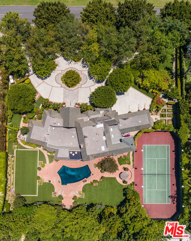 Behind private gates, rests a secluded Beverly Hills French Country Manor retreat. Soaring, circular foyer & grand formal living room w/ high ceilings, seating area, FP & walls of glass displaying views of park-like grounds. Voluminous space, high ceilings, built-in shelves, ambient light & hardwood flooring thruout the 8,200sf home. Ideal for entertaining with sumptuous family room, bar, over-sized FDR & wine cave. Formal rooms are both intimate & inviting. Chef's kitchen boasts vaulted ceiling, skylights & butler's pantry. Adjacent sunroom features rear pool/gardens views. Main floor offers office w/ ensuite bath, ensuite guest bedroom, private guest suite & maid's quarters/gym. Lavish master suite encompasses entire 2nd floor & showcases sitting area, FP, terrace & opulent his/her baths w/ walk-in's, sauna & private office. Additional amenities: elevator, security system, tennis court, pool, 3-car garage & circular motor court. A sophisticated offering in the center of it all.