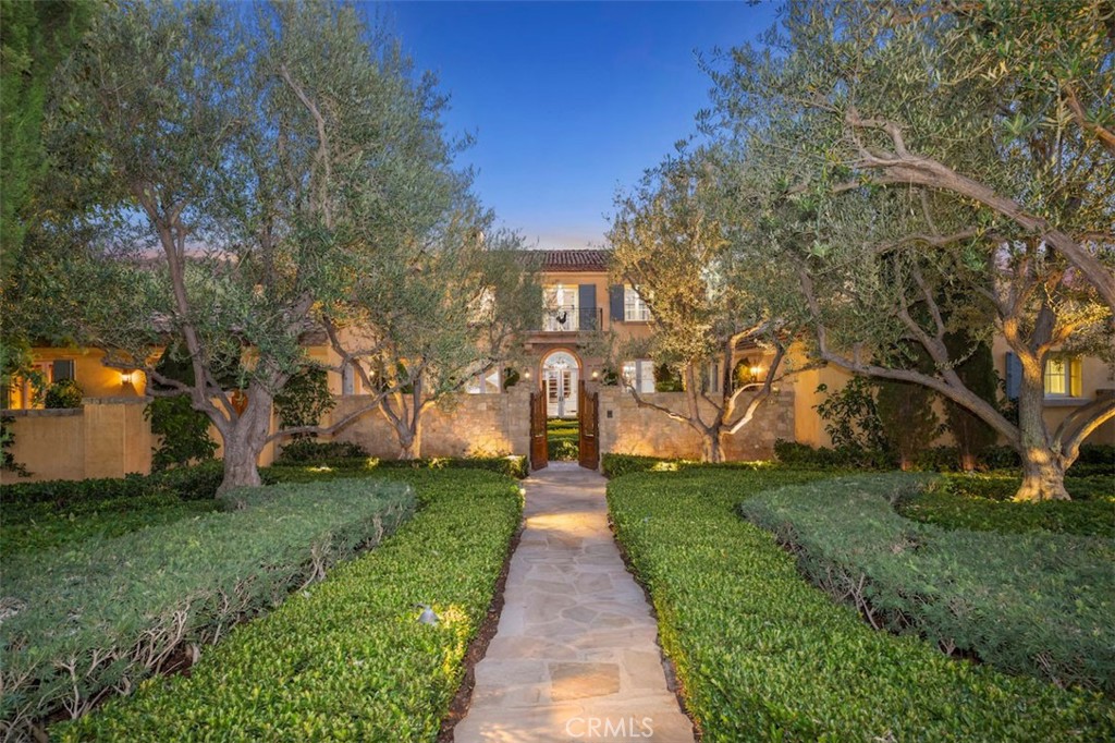 Behind the gates of iconic Shady Canyon, where estate homes blend harmoniously with nature, this French Provincial estate is a masterclass in architectural grace and enduring sophistication. Positioned on an expansive lot with panoramic views of preserved hillsides and rolling canyons, the home feels worlds away- yet remains minutes from the vibrancy of Orange County’s coastal and cultural attractions. The home opens with a formal living room anchored by a limestone fireplace and sweeping views beyond a wall of French doors. Sunlight filters through illuminating hand-finished walls, beamed ceilings, and herringbone wood floors that move seamlessly throughout. The kitchen, warm and welcoming, is outfitted in bespoke cabinetry and accented with artisanal tile work. It transitions naturally into the family room, where a custom bar offers a sophisticated focal point for casual gatherings. From here, the space opens to outdoor terraces where soft breezes and hillside stillness elevate every open-air moment. A separate dining room and salon offer elegant venues for entertaining. At the heart of the home lies a stunning game room-library, a richly layered retreat with custom built-ins, serene views of the lush grounds, and space to unwind or gather. Alternately, this dynamic space can serve as the fifth en suite bedroom. On the second level, the primary suite occupies its own private wing, with a spa-like bath, dressing room, and garden-framed views that meet unbroken vistas of the surrounding hills that foster serenity. Additional guest suites echo the same understated elegance and include a main-level junior primary suite which offers the scale and comfort of a full primary retreat and private access to the grounds- ideal for guests, extended family, or those seeking single-level living. Outdoors, the landscaping is nothing short of poetic: manicured hedges and olive trees evoke a European countryside, while tiered gardens, a tranquil zero-edge pool, and uninterrupted sight lines to untouched terrain create a daily experience of retreat. A built-in barbecue and adjacent fireplace sitting area invite relaxed dining and fireside conversation. Also noteworthy is the upstairs bonus room currently serving as a den or media space, elevator, and 3 car garage with gated motor court. Live artfully, privately, and completely with Shady Canyon’s amenities offering 24-hour guard gates, cycling and walking trails, pickleball, tennis, swim facilities, playground and more.