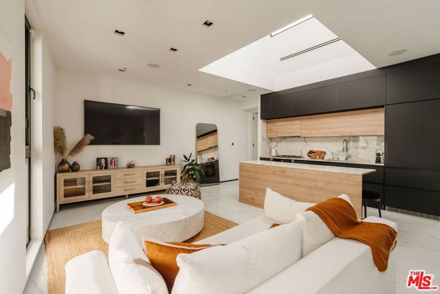 Designed by Lorcan O'Herlihy Architects, this boutique penthouse is part of an eight-residence collection in one of Los Angeles' most iconic neighborhoods. Completed in 2019, the home pairs minimalist design with a palette of large-format Italian tile and European white oak, while a private rooftop terrace provides a rare vantage overlooking the city. Anchored by a striking double-height skylight, the primary living space is drenched in natural light from above. The open kitchen grounds the residence in a sleek, modern aesthetic with matte black European cabinetry, a waterfall-edge island, and a suite of fully integrated Miele appliances. Throughout the home, trimless recessed lighting is subtly embedded within the nine-foot ceilings, maintaining a clean, uninterrupted profile. Triple-glazed, floor-to-ceiling windows with integrated Venetian blinds line the living room, offering a streamlined finish and premium thermoacoustic performance. In the bedroom, European white oak floors complement a custom-grade wardrobe-style closet set behind white glass sliding doors. The dual-access bath is enveloped in matte black Italian porcelain, featuring a floating Corian-topped vanity, an expansive frameless glass shower, and en suite laundry. A 600 square-foot  private rooftop terrace extends the home upward, offering sweeping, unobstructed views over West Hollywood. With a south-facing exposure, it is bathed in sunlight from morning to evening and perfectly positioned for spectacular sunsets. Moments from the Sunset Strip and Melrose Place, the residence sits near many of the city's most celebrated restaurants, shops and design destinations. Sunset Tower, Connie and Ted's, Ggiata, and Chateau Marmont are all close by, while the three-Michelin-starred Somni brings one of the country's most acclaimed dining experiences within easy reach. Barry's offers a premier fitness studio in the neighborhood, and both Gelson's and Whole Foods provide everyday essentials just minutes away. This is a rare opportunity to own a stunning luxury penthouse with a large private outdoor space in one of West Hollywood's most desirable locations.