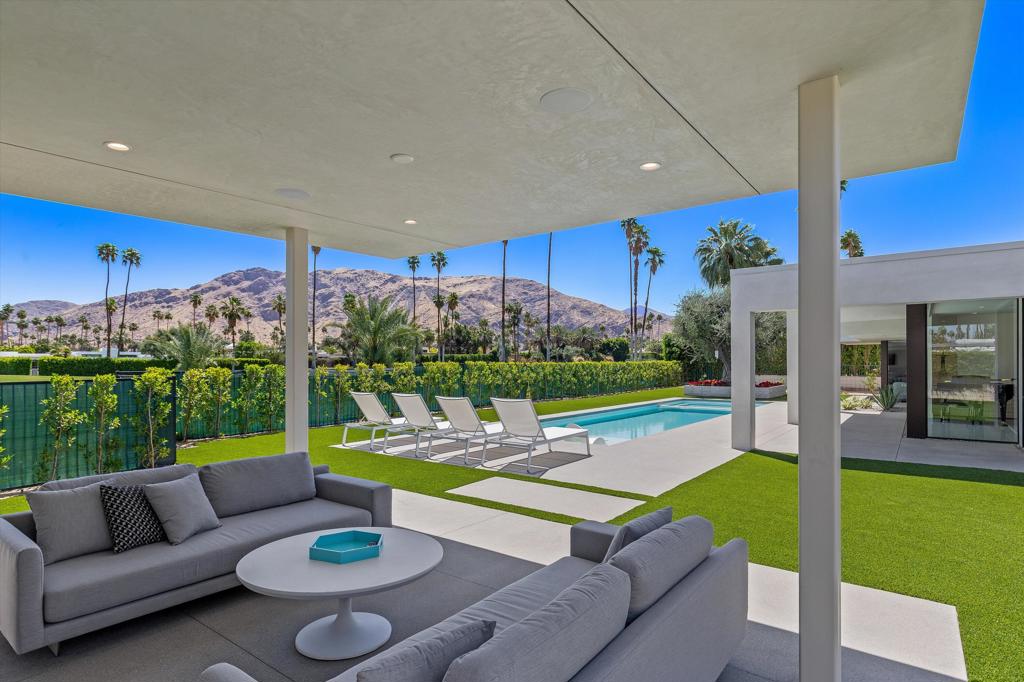 Poised in the coveted Indian Canyons neighborhood, this architecturally stunning residence once home to William Demarest of My Three Sons--has been meticulously transformed by acclaimed architect Lance O'Donnell of O2 Architecture. The result is a breathtaking fusion of classic Mid-Century charm and modern elegance, executed through a comprehensive down to-the-studs renovation. Perfectly positioned on the 13th fairway, the home boasts multiple outdoor living spaces with sweeping eastern and western mountain views ideal for both sunrise coffees and sunset cocktails. Walls of glass vanish to create an effortless indoor/outdoor lifestyle, while the expansive open-plan interiors are anchored by striking Terrazzo tile floors, a sophisticated bar, and a dramatic stone fireplace that invites both conversation and relaxation. The gourmet kitchen is a chef's dream, featuring custom walnut cabinetry, top-of-the line Thermador double ovens and cooktop, a Dacor refrigerator, Bosch dishwasher, and a Z Line beverage fridge. A stunning 15-foot island provides generous space for daily living or elevated entertaining. The primary suite is a true retreat, offering a spa-inspired bathroom that evokes the tranquility of a five-star resort. Two additional guest suites each include private luxury baths, offering comfort and privacy for visitors. Smart home technology via a full Control4 system ensures seamless automation throughout. Additional highlights include a spacious, well-appointed laundry room with built-in cabinetry and a second refrigerator zone. Outside, enjoy a brand-new pool and spa with a tanning shelf, water feature, and Pentair automation. A sleek outdoor pavilion with fireplace creates a cozy haven for cooler desert evenings. This is not just a home--it's a fully realized lifestyle experience, brought to life with the finest materials, exceptional design, and timeless sophistication.