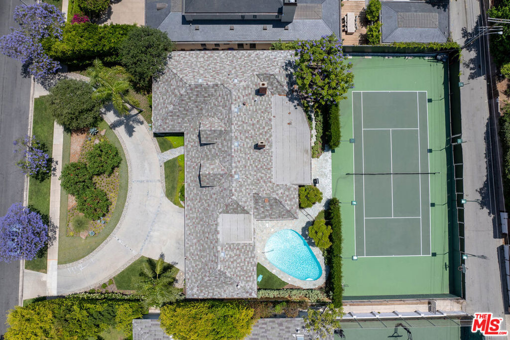First Time Available in Over 50 Years Prime Beverly Hills Flats Estate Opportunity. Located on one of the most prestigious streets in the Beverly Hills Flats, this rare offering sits on an expansive 21,200+ sq. ft. elevated lot, providing exceptional potential to renovate, expand, or build a world-class estate. Surrounded by mature jacarandas and lush landscaping, the existing residence is set back from the street behind a wide circular driveway, offering privacy, charm, and a commanding presence. The current 5-bedroom, 5-bath traditional-style home features a spacious layout, including a primary suite, guest suite, and multiple gathering rooms filled with natural light. Classic details like stonework, dormer windows, and a slate roof lend timeless curb appeal, while the generous footprint offers versatile living and entertaining options. Outdoor amenities include a north-south tennis court grandfathered in which cannot be replicated under current zoning and a sparkling pool, both positioned for privacy and usability. Set on a gentle rise, the lot may afford partial second-story glimpses of surrounding hills depending on future architectural design.Whether you restore the existing residence or design a bespoke luxury compound, this is one of the last remaining large parcels in the Flats with such favorable topography, scale, and positioning.
