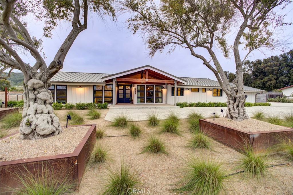 Nestled on a spacious 1.12-acre lot with scenic views of Hollister Peak and rolling valley hills, this stunning modern farmhouse offers both style and versatile income generation. Extensively remodeled in 2020, the property includes a 5-bed 3-bath main home, a 1-bed 1-bath guest suite, and a detached 2-bedroom, 2-bath rental unit, all meticulously designed for comfort and privacy. The main residence, currently operating as an Airbnb, is organized into two wings separated by central living spaces. The kitchen showcases custom cabinetry, modern appliances, and a breakfast bar peninsula opening to two living areas, one featuring a fireplace and expansive 16-foot sliding doors leading to the patio. The east wing includes the primary suite with an ensuite bathroom and deep soaker tub, two additional bedrooms sharing a bathroom, a laundry room, and cozy lofted reading nooks. The west wing provides two additional bedrooms and a shared bathroom equipped with a shower and bathtub. The 2020 remodel highlights include cement fiber siding, custom vertical fir windows, an insulated metal roof, new flooring, updated fixtures, a high-efficiency furnace, and a tankless water heater. Custom-designed patios and carefully planned landscaping enhance the outdoor living experience. The backyard is fully fenced and landscaped, featuring a large patio, lawn, fire pit, and seating areas perfect for entertaining or relaxing with picturesque views. Beyond the main residence there are two rental units: an attached one-bedroom one-bath apartment with a private entrance and a separate two-bedroom, two-bath unit featuring a two-car garage, beautiful kitchen, and private yard. Further property features include owned solar panels, two recently installed septic systems sized for future ADU expansion, a private well, and natural gas utilities. The property boasts olive trees in custom planters, magnolias, passion fruit guava plants, automated drip irrigation, and a custom chicken coop with additional space for animals or hobby farming. Situated among larger ranch properties, the area offers peaceful countryside living, neighboring horses, and nearby equestrian activities. The convenient location places you within a ten-minute drive of Morro Bay beaches, Montaña de Oro trails, and the vibrant downtown area of San Luis Obispo. This property offers a unique combination of quiet country living, modern amenities, and excellent income opportunities—don't miss this rare find on the Central Coast.