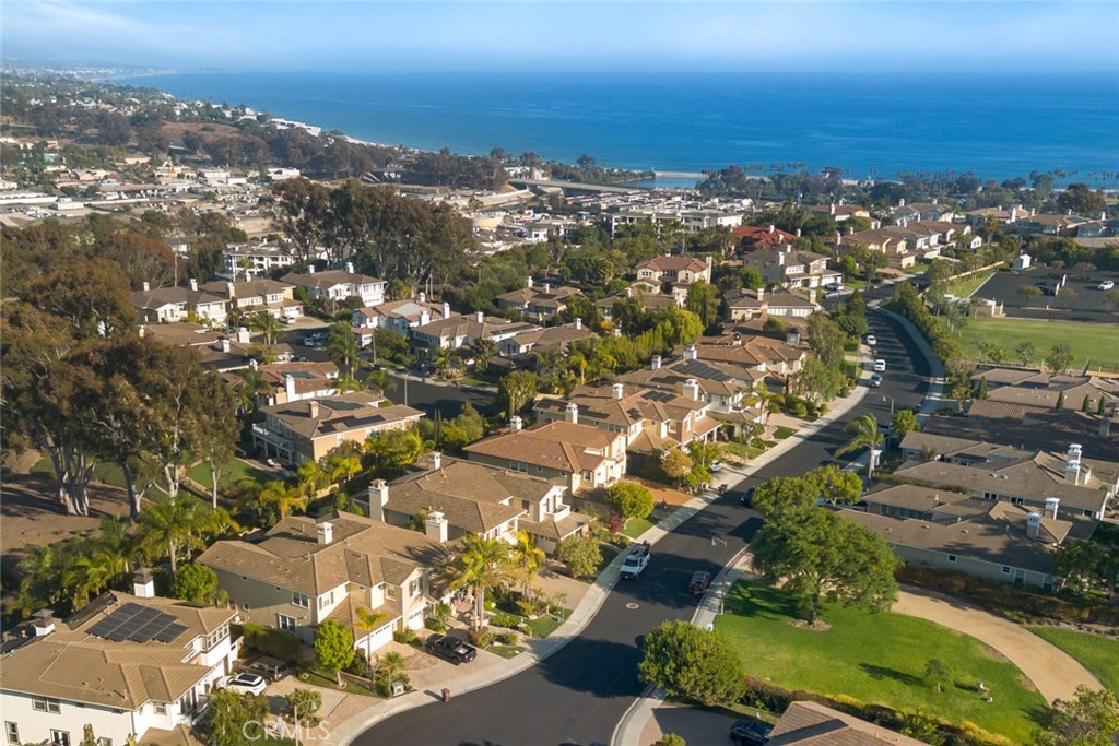 Elegant, stately and impressively sized, this custom-caliber residence presents an exceptionally rare opportunity to own behind the gates of Dana Point’s exclusive Bal Harbour collection, where only 43 homes are featured. Enviably located across the street from a beautiful neighborhood park on a large cul-de-sac homesite that backs to open space, the luxurious home is perfectly positioned to capture scenic views of Saddleback Mountain, hills and evening lights. Refined landscaping and custom hardscaping embellish the front yard, while a welcoming patio leads the way to a double-door entrance. The home’s generous proportions are apparent upon arrival, with lighted art niches flanking the entry and a double-height foyer showcasing a stunning three-tier staircase. Natural light bathes massive living and dining rooms, where a fireplace, walk-in wet bar with refrigerator, and French doors opening to the backyard enrich sublime entertaining. The casual and sunny family room also offers backyard access and hosts a fireplace, built-ins and a seamless transition to the kitchen, where an island, breakfast area and white cabinets are displayed. A suite of stainless-steel appliances and smooth granite countertops with a full backsplash make mealtime prep virtually effortless. Approximately 5,264 square feet, this sought-after home reveals four
ensuite bedrooms, including one on the main floor, five- and one-half baths, an office, and a game room with private bath and walk-in wet bar. Three balconies bring the outdoors into the second floor, including an expansive view deck off a primary suite that boasts a fireplace, sitting area, tray ceiling and a wall of windows and French doors. The opulent primary bath is lavishly appointed with a sit-down vanity, two sinks, two commodes, a soaking tub, separate shower and expansive walk-in closet. Solar power enhances the home’s energy efficiency, and a split three-car garage, hardwood flooring, designer carpet in bedrooms, crown molding, ceiling fans and custom built-ins are featured. Stylish entertaining is easy in a resort-inspired backyard with swimming pool and spa, a custom stone fireplace with circular patio, manicured landscaping, a lawn, spacious covered patio and a palapa-style built-in BBQ bar. The prestigious Bal Harbour enclave is less than one mile from Doheny Beach and Dana Point Harbor, and Del Obispo Park, Dana Hills High School, shopping centers and restaurants are minutes away.
