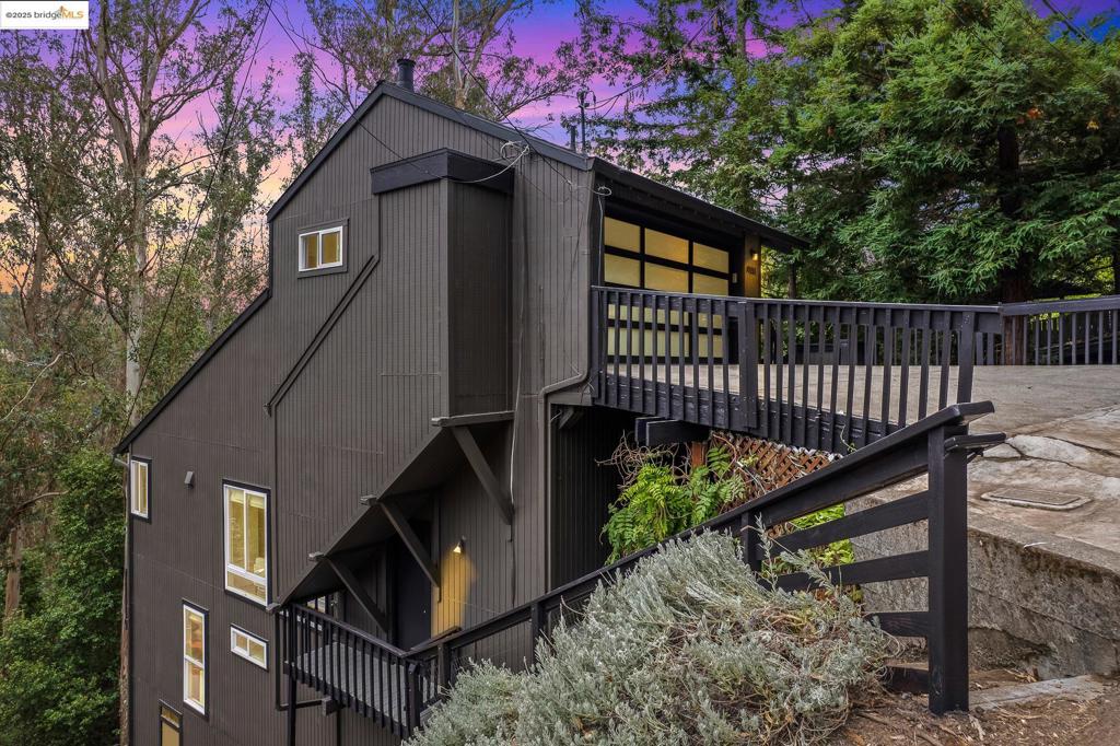 Enjoy light-filled, open-concept living in this beautifully updated Montclair retreat. The great room dazzles with a natural stone-clad fireplace, vaulted ceilings, and a wall of windows framing lush forest views. The adjacent dining area is centered by a modern Sputnik chandelier, while the stylish kitchen features quartz countertops, subway tile backsplash, and stainless appliances. A cozy study just off the main room offers the perfect space to work or unwind. Also on this level: a design-forward half bath, an additional den, and a full bedroom with exterior access. Downstairs, the dramatic primary suite offers tree-lined tranquility with custom lighting, a spa-worthy bath with dual-sink vanity, matte black fixtures, and walk-in shower. Two additional bedrooms with peaceful outlooks, a floating vanity hall bath, and laundry station complete the level. Multiple decks create seamless indoor-outdoor living, while the lower-level spa retreat—with sauna, gym, and renovated half bath—adds an element of luxury. The attached garage provides direct home access and ample storage. Ideally located near Montclair Village shops, cafés, and the Montclair Railroad Trail, with easy access to Highway 13 for commuting to SF, San Leandro, or Walnut Creek.