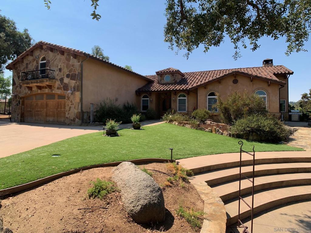 Beyond a private, gated entry lies a world meant for gathering, living, and dreaming. On a flat, useable acre framed by mature trees and golden westerly sunsets, three distinct residences create a rare multi-generational haven. The Tuscan-inspired main home, rich with high ceilings, 8-foot custom doors, earth-toned finishes, and sunlit spaces, invites you to linger—whether by the family-style kitchen with its granite island and black cabinetry, or fireside under the stars beside the newly built-in firepit. The permitted loft above the garage transforms into a chic studio rental, while the cottage-inspired front home offers two bedrooms, a warm fireplace, and a private walled patio. Between them, a pool house with bath and laundry stands ready for summer days beside the sparkling inground pool. With 7 bedrooms, 5.5 baths, and over 5,400 sq. ft. of living space, this compound offers 5 laundry facilities, 2 septic systems, paid-off 38-panel solar, paved RV parking with hookups, and an oversized driveway for endless guests. Wander the small orchard—avocado, grapefruit, lemon, lime, apricot—and imagine more. Here, life is secure, serene, and full of possibilities, where privacy meets connection in perfect harmony.