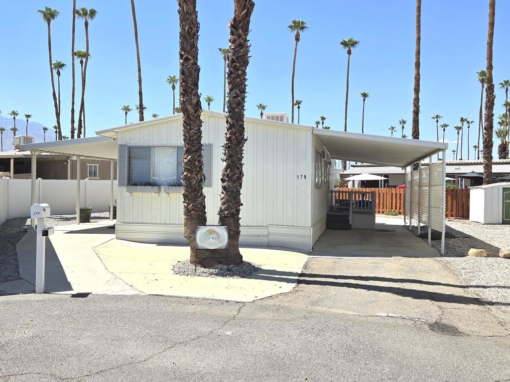 Located in the Royal Palms 55+ community, 179 Butterfield, a 1963 Mayflower 960 sq. ft., two bedroom mobile home with two 3/4 baths, is a stunningly beautiful desert retreat that has been elegantly appointed and meticulously maintained. Entry to the residence is through a lovely west-facing deck with steps that open into the tasteful, bright, carpeted living room; immediately to the left is the dining area with lovely built-ins, a modern chandelier and striking laminate flooring that extends into the adjacent kitchen. Equipped with a four-burner cooktop and an original (working) oven, the kitchen is light, airy and well-organized. Down a short hallway is a bright and roomy guest bedroom with amazing built-ins. Opposite is the guest bathroom with a shower stall and updated vanity. At the east end of the home is the spacious, well-appointed primary bedroom with ensuite bath with tub. A notable feature of this lovely home is the striking high-ceilings that exist throughout the structure. Tandem parking is under a carport awning on the east side of the home; there is a shed on the premises as well. Climate control in the home is through central AC / heat with new Nest thermostat, and a swamp cooler as well; ductwork under the home was renewed in 2022. Royal Palms has two community laundry facilities within the park, each of which within easy reach. 179 Butterfield is sold fully furnished though there is a short list of seller exclusions. Approval by park management at the Royal Palms is required for purchase; monthly space rent for this home will be $892.00 per month for the new owner, though that figure must be verified by any buyer.