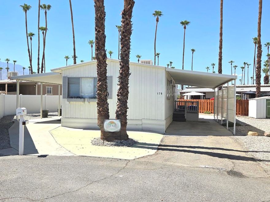 Located in the Royal Palms 55+ community, 179 Butterfield, a 1963 Mayflower 960 sq. ft., two bedroom mobile home with two 3/4 baths, is a stunningly beautiful desert retreat that has been elegantly appointed and meticulously maintained.  Entry to the residence is through a lovely west-facing deck with steps that open into the tasteful, bright, carpeted living room; immediately to the left is the dining area with lovely built-ins, a modern chandelier and striking laminate flooring that extends into the adjacent kitchen.  Equipped with a four-burner cooktop and an original (working) oven, the kitchen is light, airy and well-organized.   Down a short hallway is a bright and roomy guest bedroom with amazing built-ins.  Opposite is the guest bathroom with a shower stall and updated vanity.  At the east end of the home is the spacious, well-appointed primary bedroom with ensuite bath with tub.   A notable feature of this lovely home is the striking high-ceilings that exist throughout the structure.  Tandem parking is under a carport awning on the east side of the home; there is a shed on the premises as well.  Climate control in the home is through central AC / heat with new Nest thermostat, and a swamp cooler as well; ductwork under the home was renewed in 2022.  Royal Palms has two community laundry facilities within the park, each of which within easy reach.  179 Butterfield is sold fully furnished though there is a short list of seller exclusions.  Approval by park management at the Royal Palms is required for purchase; monthly space rent for this home will be $892.00 per month for the new owner, though that figure must be verified by any buyer.