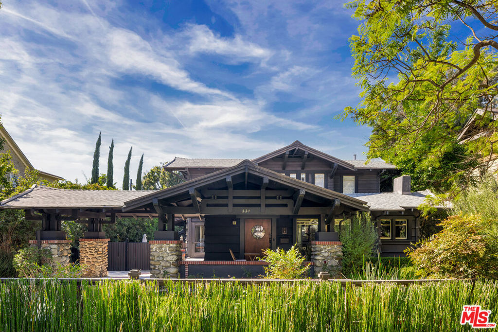 Nestled in the heart of St Andrews Square, this exquisite home is a recognized Los Angeles Historic-Cultural Monument built around 1912. Crafted by visionary architect Arthur S. Heineman, it exemplifies the beauty of California Craftsman design from the Arts and Crafts era. Indoors you'll discover a captivating blend of original craftsmanship and modern elegance. The living room highlights vintage details showing the home's rich history, including original hardwood flooring, boxed beam ceilings, and a cozy inglenook. An elegant dining room connects to a wine cellar, and the family-media room has a convenient powder room along with a dedicated office area. The kitchen beams with natural light, making it ideal for both casual dining and gourmet cooking. Outfitted with high-end appliances, a spacious island, and a charming breakfast nook, it flows seamlessly into the beautifully landscaped backyard. Upstairs, you'll find two bedrooms that share a recently remodeled bathroom. The spacious primary suite boasts a luxurious new bathroom equipped with a Toto toilet, dual walk-in closets, and a cozy sitting area. Outside, the expansive lot offers multiple outdoor spaces perfect for gatherings, including a spacious vine-covered pergola and a fire pit area, in addition to a deck off of the kitchen and family room in the back, and a covered porch in the front. There's also a versatile guest house or studio with a half bath. With ample parking for six vehicles, this one of a kind property is nearby Larchmont Village, K-Town, The Grove, and Downtown LA, making it the ideal blend of historical charm and modern convenience.