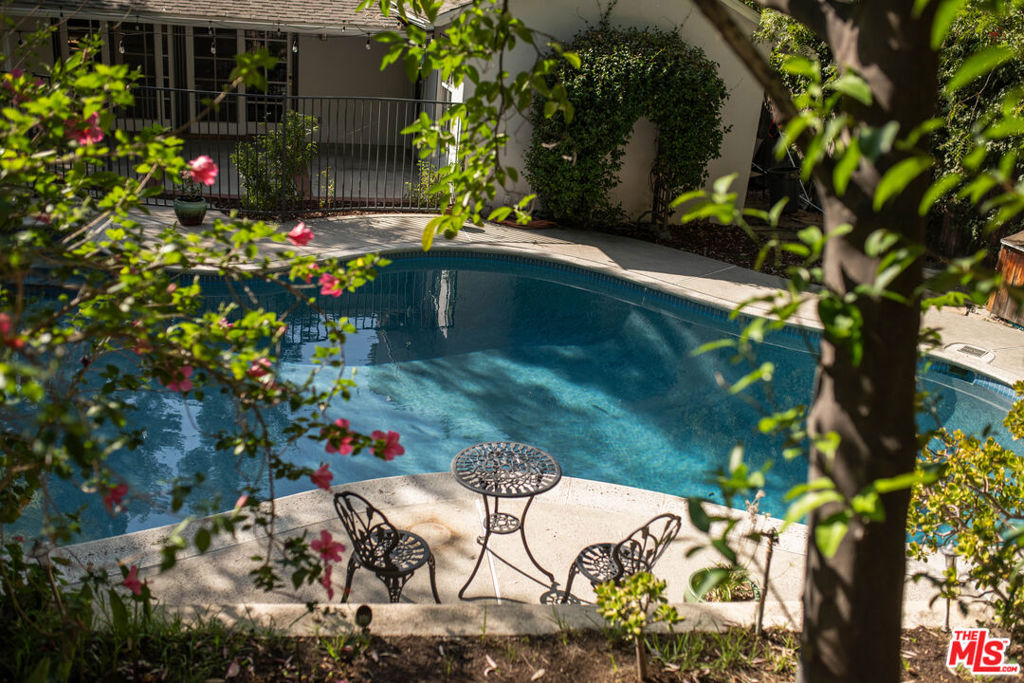 Sun-Drenched Mid-Century Gem South of the Boulevard. Set on a generous 11,000+ sq ft lot, this property is your private retreat. Tucked away on a serene Woodland Hills street, this timeless mid-century home blends original charm with thoughtful updates. Sunlight pours through oversized windows, highlighting warm wood details, original built-ins, and the cheerful vintage kitchen with its sunny yellow tile. Sliding glass doors from both the living room and primary suite open directly to the outdoors, creating an easy flow between indoor comfort and outdoor tranquility. Outside, the backyard unfolds as a true oasis; serene, lush, and home to one of the largest pools in the neighborhood. Just above, a rare flat pad of land offers endless potential: envision a garden, play space, or creative project uniquely yours. Inside, the airy layout offers generous living and entertaining spaces, complemented by tasteful updates including enhanced electrical, a new oven, fridge, and foundational improvements for added peace of mind. Perfectly situated south of the Boulevard, in a coveted location close to Ventura's dining, shopping, and cafes while still tucked away in the quiet calm of the canyon.