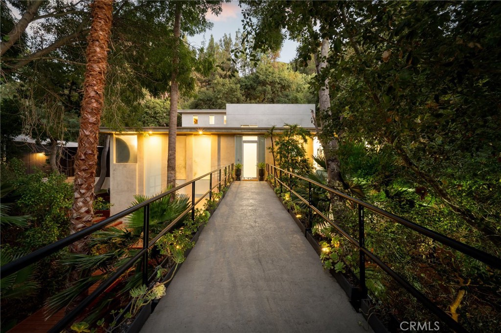 Welcome to the BridgeHouse Estate, a privately gated celebrity retreat hidden in the hills of Studio City. Set on a sprawling 15,000+ sf lot and surrounded by lush greenery, this property is introduced by a dramatic 60-foot bridge that stretches over a natural creek and guides you to the front door. Inside, the beautifully updated open-concept floor plan boasts lofty 10 ft ceilings and expansive floor-to-ceiling windows that flood the space with warm natural light. The designer kitchen is a culinary enthusiast's dream, equipped with top-of-the-line appliances, elegant quartz countertops, custom cabinetry and a massive waterfall island with seating. Open to the kitchen, the spacious living room and formal dining room are illuminated by sleek modern fixtures, including a statement Hanami chandelier and state-of-the-art Lazer Line lighting system. Step outside to a secluded backyard retreat highlighted by a sun-drenched patio, low-maintenance artificial turf yard and built-in BBQ, perfect for effortless outdoor entertaining. The second floor offers a full bathroom and two bedrooms that have been combined into a single, expansive space, but can easily be reconfigured back into individual rooms if desired. On the upper level there’s a flexible loft space and two additional bedrooms/bathrooms, including a chic primary suite that features a custom walk-in closet and sumptuous bathroom, complete with a rainfall shower, double vanity and soaking tub bathed in natural light. You’ll also find an expansive rooftop terrace with treetop views and a separate deck area with a private hot tub. Additional highlights include a laundry area, finished two-car garage with ac (offering potential for an office, gym, studio or bonus living space), EV charging station and potential to expand the interior living space. Ideally located South of the Boulevard within the coveted Carpenter School District, this one-of-a-kind architectural masterpiece is just minutes away from the vibrant shopping and dining scene found along Ventura Boulevard, Fryman Canyon hiking trails, the Sunset Strip and so much more.