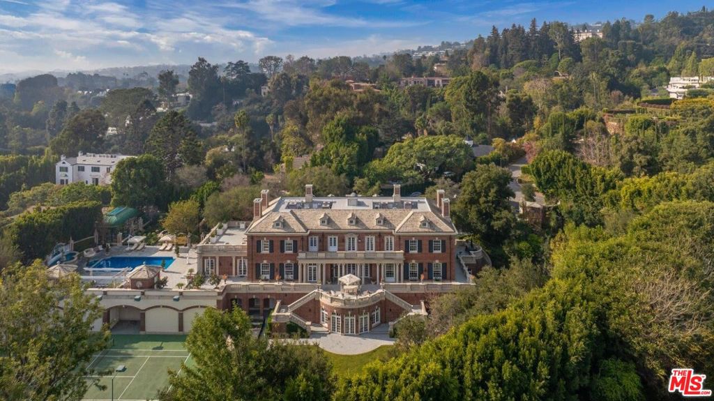 Situated in Bel-Air's exclusive East Gate, Rosewood is a Georgian masterpiece by renowned architect Richard Manion, encompassing approximately 23,000sf of unmatched elegance. Behind private gates, a grand horseshoe motor court leads to a stately red brick facade, accented by limestone moldings, ornate columns and elegant blue shutters. Meticulously landscaped grounds span 1.51 acres, offering serene pathways and vibrant greenery. The grand foyer, crowned by an oval skylight dome, bathes the black-and-white marble floors in natural light, while a sweeping spiral staircase sets the tone for the residence's grandeur.The formal living room features 12-foot ceilings, intricate crown moldings, a grand fireplace and floor-to-ceiling glass doors that open to picturesque grounds. Adjacent, the bespoke office exudes sophistication with rich mahogany paneling, marble fireplace and coffered ceilings. The luxurious formal dining room designed for large gatherings is exquisitely appointed with custom cabinetry and a marble fireplace.The gourmet kitchen offers marble countertops, custom white cabinetry and top-of-the-line appliances. An expansive marble island serves as the focal point, while the butler's pantry adds functionality. The informal dining room opens to a vast wraparound terrace, perfect for alfresco entertainment. The inviting informal living room features a marble fireplace, wood-paneled coffered ceiling and gold detailing. French doors seamlessly connect the interior to the lush grounds beyond.Ascending to the second level, the sumptuous primary suite leads into a sitting area with a high ceiling and terrace access. Private sliding doors open into the suite's sleeping quarters, featuring a marble fireplace, wood flooring and ambient light. Dual luxurious marble bathrooms offer gracious walk-in closets, marble soaking tubs and separate showers. Four generous guest suites, one with terrace access, complete the level.Descending to the entertainment area, a private guest suite, gym, massage room, wine cellar and secondary kitchen await. The grand oak-paneled ballroom, complete with a stage and custom built-in bar, accommodates up to 120 guests. Expansive glass doors lead to pristine grounds with a championship N/S tennis court, sprawling lawns, wrought-iron gazebo, treehouse, swimming pool, spa, fountains, lounge areas, built-in BBQ and bar and conservatory.Additional luxurious amenities include a subterranean fourth level with a 12-car showroom and whimsical vintage soda fountain diner, an elevator, manager's office, utility room, ample storage, state-of-the-art security and staff quarters. Impeccably designed and thoughtfully appointed, Rosewood epitomizes sophisticated living in one of Bel-Air's most prestigious enclaves. Includes 9 bedrooms (3 are service quarters), 11 full bathrooms, 9 powder rooms.