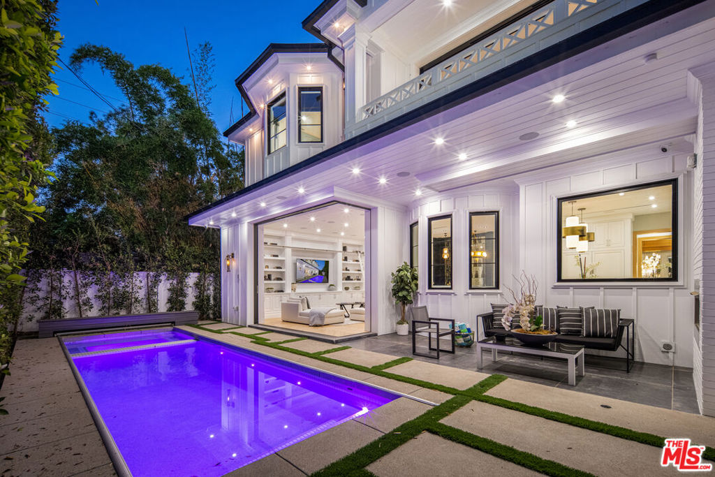 Spectacular new-construction transitional tucked behind walls and gates on a private Beverly Grove lot. Thoughtful design and top-tier finishes throughout: formal living and dining, a home theater, main-level guest suite, powder room, and a chef's kitchen with Sub-Zero/Wolf, butler's pantry, and breakfast nook open to a large family room with wet bar and retractable floor-to-ceiling glass. Outdoors: covered patio, alfresco dining, and a bespoke white-pebble pool/spa. Upstairs offers three en-suite bedrooms plus a regal primary with dual designer closets, spa bath, private balcony, and a study/media lounge. Oak floors with brass inlay, Control4 smart home, central vac, laundry (W/D included), and an attached 2-car garage. Moments from The Grove, boutiques, and top dining.