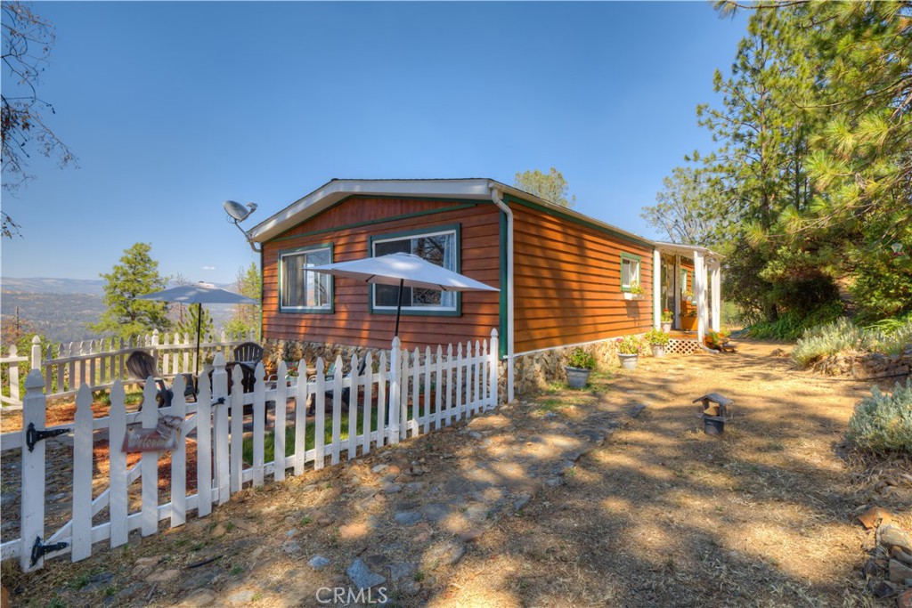 PANORAMIC VIEWS OF LAKE OROVILLE AND MOUNTAINS! Vacation home, Airbnb, or permanent home...you make the choice!! This adorable FURNISHED "cabin style" home sits way up on the mountain with breathtaking views! The home feels so comfortable with beautiful tile and laminate flooring, wood burning stove, decorative tile in the kitchen, open floor plan, lots of windows for natural lighting and spectacular views from almost ALL of the windows!! This lovely home also has an attached covered enclosed back porch to relax and enjoy the great outdoors! The property has plenty of space for gardening, newer pump system for the well, and is just a few miles from the free boat launch up String town road. As a welcome addition, this home comes partially furnished! Call today for your appointment to see this beautiful home and property!!