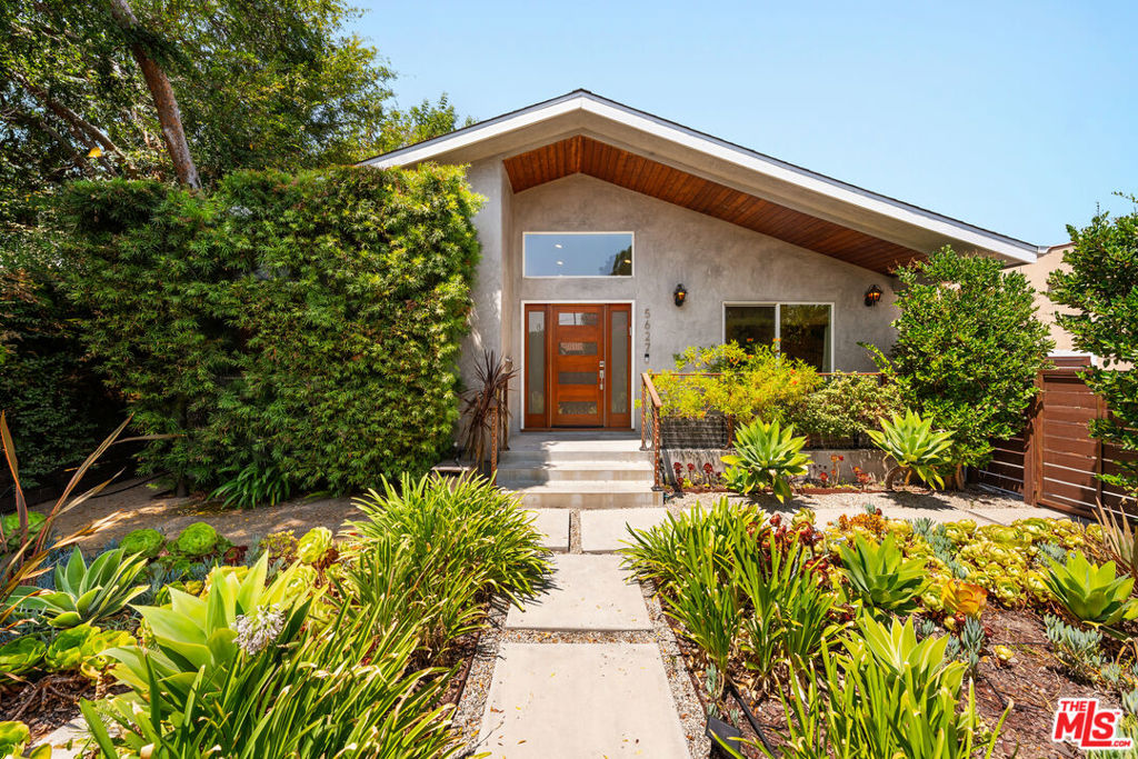 Reimagined with exceptional craftsmanship and taken down to the studs, this turnkey designer residence blends contemporary comfort with thoughtful functionality. Behind a sleek modern entry door, soaring 13-foot ceilings greet you in the sun-drenched great room. An open-concept space adorned with white oak flooring, smooth plaster walls, integrated LED lighting, and custom stained wood and glass doors that elevate the home's refined aesthetic. The chef's kitchen is a showpiece, featuring pristine white quartz countertops, an oversized waterfall island with bar seating, and premium Bosch stainless steel appliances including a 30" five-burner range, hood, and dishwasher. Custom cabinetry provides ample storage, seamlessly integrating style and practicality. Bathed in natural light, the open dining room boasts a statement chandelier and serene views of the lush backyard, an ideal setting for intimate dinners or lively gatherings. The primary suite is a sanctuary complete with designer flooring, curated lighting, a floating vanity, custom mirrors, and a beautifully built-out walk-in closet. Two additional en-suite bedrooms offer privacy and comfort for family or guests, each appointed with their own luxe renovations. Step outside to a resort-inspired backyard retreat, designed for year-round entertaining. Enjoy evenings around the built-in fire pit, unwind while you dine alfresco under bistro lighting, or enjoy an afternoon on the grass surrounded by tall mature hedges. Fresh sod, drought-tolerant landscaping, and full privacy fencing complete this inviting outdoor haven. The finished single-car garage currently functions as an elegant home office featuring custom white oak storage built-ins and French doors ideal for creative professionals or remote work, alongside a separate home gym. Notable upgrades include custom window treatments, dual-pane windows, newer copper plumbing, dual electrical panels and wiring, central HVAC, a tankless water heater, and a sleek aluminum-trimmed glass garage door. Ideally situated within the Slow Street Program and just minutes from the Metro, NoHo Arts District, and the vibrant NoHo West Development, this home offers a rare blend of luxury, lifestyle, and location.