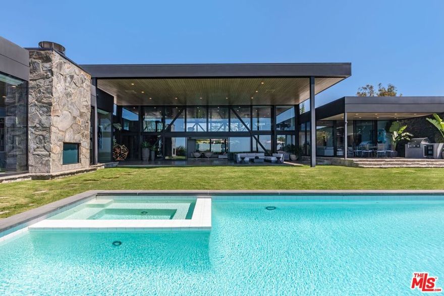 Elvis, Sinatra, Dean Martin: there's good reason that the world's style masters chose to call Trousdale home. Architectural tour de force in the most coveted location of Beverly Hills, Trousdale Estates. Originally designed in 1973 by renowned architect Amir Farr and reimagined by Belgian-born designer Maxime Jacquet, this Lautner-esque modern estate captures the essence of California living. Constructed from glass, steel, stone, and redwood, the residence spans over 8,000 SF and sits at the end of a quiet cul-de-sac. A soaring two-story living room with retractable glass walls frames sweeping city-to-ocean views and opens seamlessly to the expansive lawn, outdoor lounge, and infinity pool and spa. Inside, a sleek kitchen flows into the family room, while the interiors pay homage to the 1970s' open-space aesthetic with a sophisticated, earth-toned palette. The lavish primary suite offers its own lounge, stone fireplace, walk-in closet, and panoramic vistas. Designed for entertainment and relaxation, the estate includes a tiered screening room with state-of-the-art sound, fully integrated Crestron automation, and interiors that balance architectural drama with livable luxury in one of Beverly Hills' most exclusive enclaves.