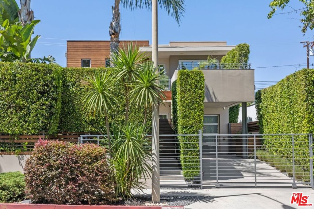 Tucked behind gates and surrounded by mature greenery, this ultra-private modern retreat sits on one of West Hollywood's most coveted blocks and epitomizes indoor-outdoor living at its finest. Just moments from Beverly Hills, the residence has been reimagined by its current owner to evoke the experience of a world-class luxury hotel. A foliage-lined entry leads into a hidden garden, a magical courtyard oasis that flows effortlessly into the living room. The first floor embraces a true open-concept design, with interiors that seamlessly expand to the front and rear gardens, creating a sanctuary of light, privacy, and calm. Wide-plank hardwood floors and a sleek fireplace anchor the living room, while the chef's kitchen dazzles with Miele appliances, a large island, and custom cabinetry. The adjacent dining and family room open onto a backyard escape complete with a covered, heater-equipped lounge, a sparkling pool with fountain, and a spa-all enclosed by soaring hedges for total seclusion. The attached garage, currently configured as a bespoke storage suite, offers flexibility for additional living, creative, or fitness space. Upstairs, the primary suite is a study in luxury, with abundant custom closets (including a converted third bedroom), refined window treatments and built-ins, a balcony, and a marble spa-like bathroom with dual sinks and a glass-enclosed shower. The second bedroom is bathed in natural light and spills onto a romantic rooftop patio. Additional amenities include a Control4 home automation system, motorized blinds throughout, and a comprehensive security system with cameras. Set in an unmatched central location, the home is minutes from the acclaimed dining, shopping, and nightlife of Robertson, Melrose, and Beverly Hills.