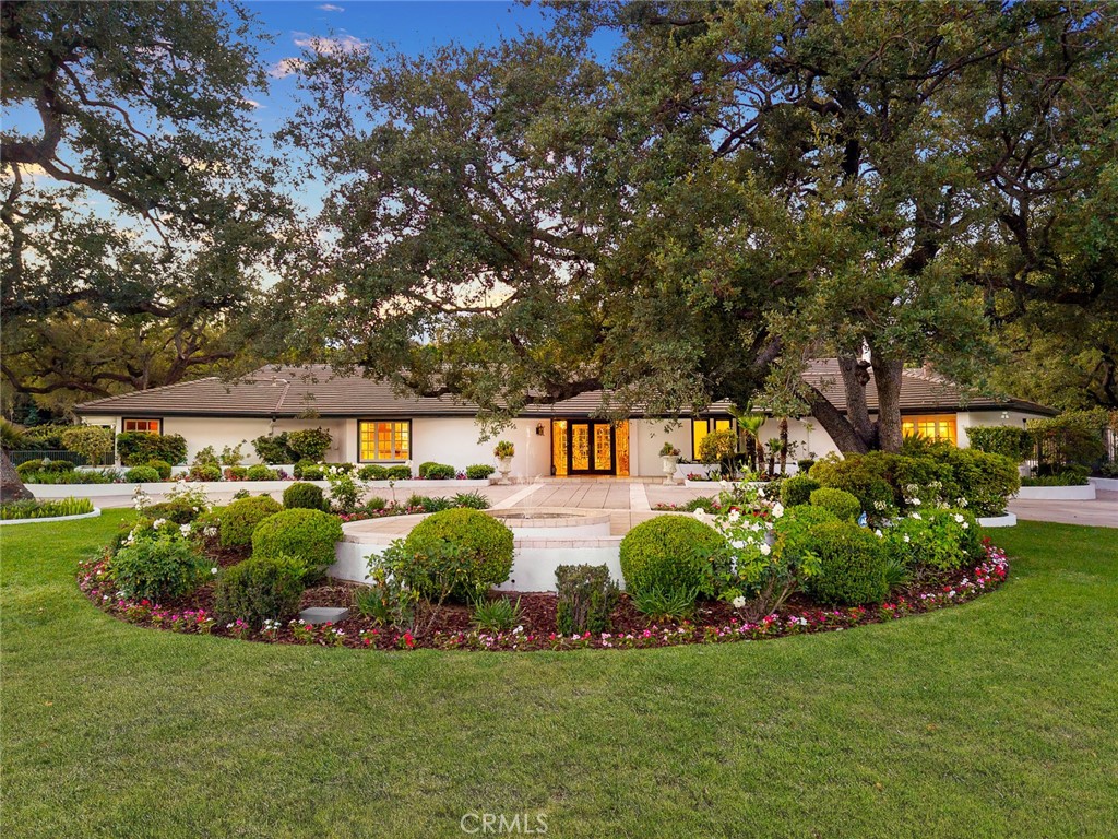 Prestigious Upper Rancho Estate in Arcadia. This distinguished estate is set on a sprawling 43,359 sq.ft. lot (144 x 301) and is beautifully secluded by mature trees and lush landscaping. On the market for the first time in over 26 years, this exceptional single-story, south-facing home offers 3,322 sq.ft. of elegant living space and an unparalleled indoor-outdoor lifestyle. A gated circular driveway provides privacy and ample parking, leading to an expansive front porch that overlooks manicured gardens and a verdant front lawn. Wrought-iron fencing encloses the beautifully landscaped grounds, creating a serene, park-like ambiance. Step through ornate double doors into a welcoming interior. Multiple picture windows frame sweeping garden views, while the generously sized living room features a striking white marble fireplace, detailed wainscoting, and walls of glass that open to the breathtaking backyard. The formal dining room exudes timeless charm with designer wallpaper and a vintage-style chandelier. The updated kitchen boasts a center island, granite countertops, custom tile backsplash, stainless steel appliances, recessed lighting, and a large picture window with front yard views. Adjacent to the kitchen, a wet bar and cozy family room open to the patio—perfect for entertaining or relaxing. This thoughtfully designed home offers four bedrooms and three bathrooms, plus a spacious office/library with built-in bookshelves and outdoor access. The east wing includes the primary suite with, large dressing area, dual sinks, spa tub, and a glass-enclosed shower. Two additional bedrooms and a shared bath complete this wing. The west wing features a separate bedroom with a bath—ideal for guests or multi-generational living. A conveniently located laundry room is just steps away. The expansive backyard is a true entertainer's paradise, complete with a covered patio, lush lawns, a sparkling pool, mature trees, and a variety of fruit trees and heirloom roses. Towering foliage and thoughtfully curated landscaping create a private oasis with scenic mountain views. Additional highlights include an attached two-car garage, central air, and award-winning Arcadia Unified School District. You'll also enjoy easy access to top-rated schools, shopping, dining, Santa Anita Park, the Arboretum, and more.
A rare opportunity to own a timeless estate in one of Arcadia’s most prestigious neighborhoods. This home is truly a must-see!